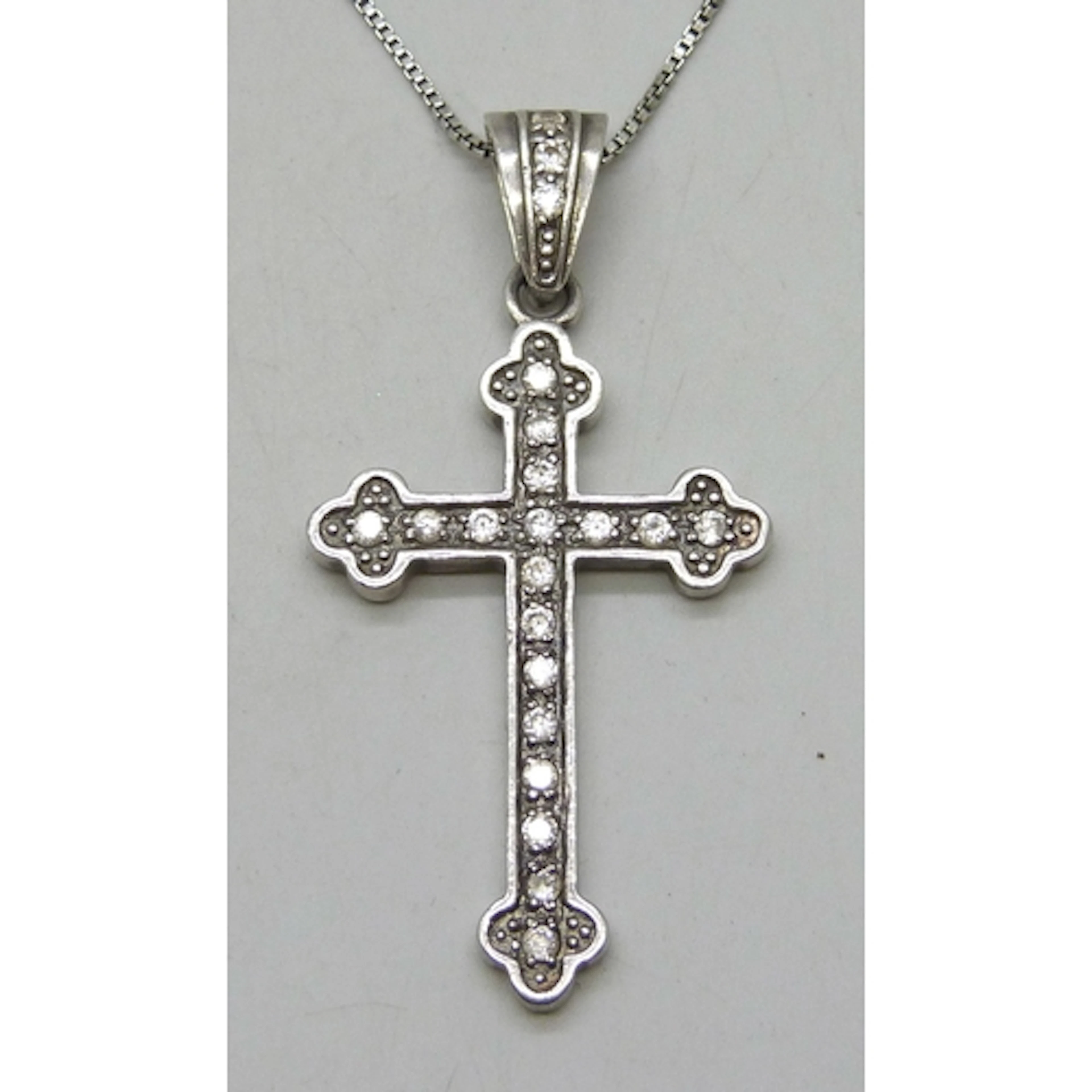 A silver cross pendant on a silver box link necklace chain, ...