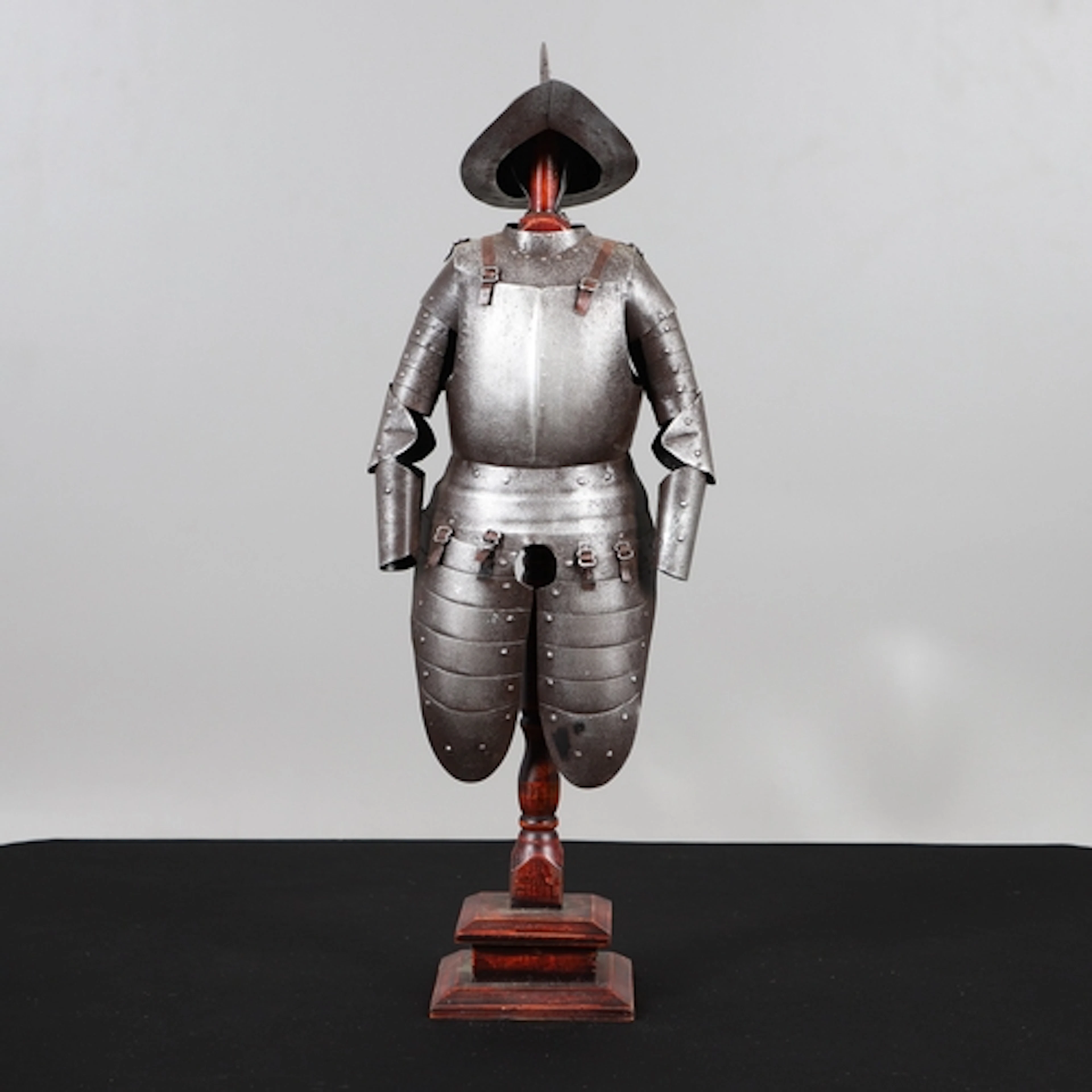 A MINIATURE PART SUIT OF ARMOUR ON WOODEN STAND. A miniature...