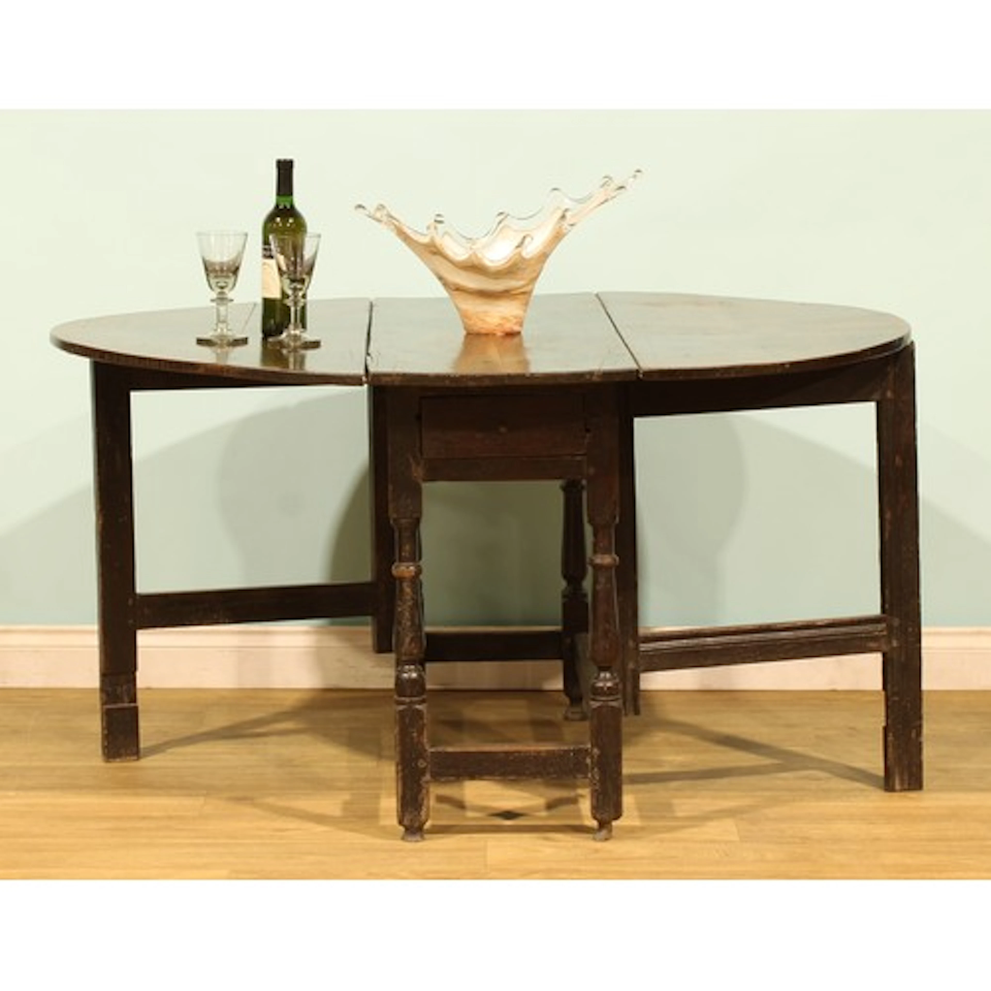 An 18th century oak gateleg table, oval top with fall leaves...