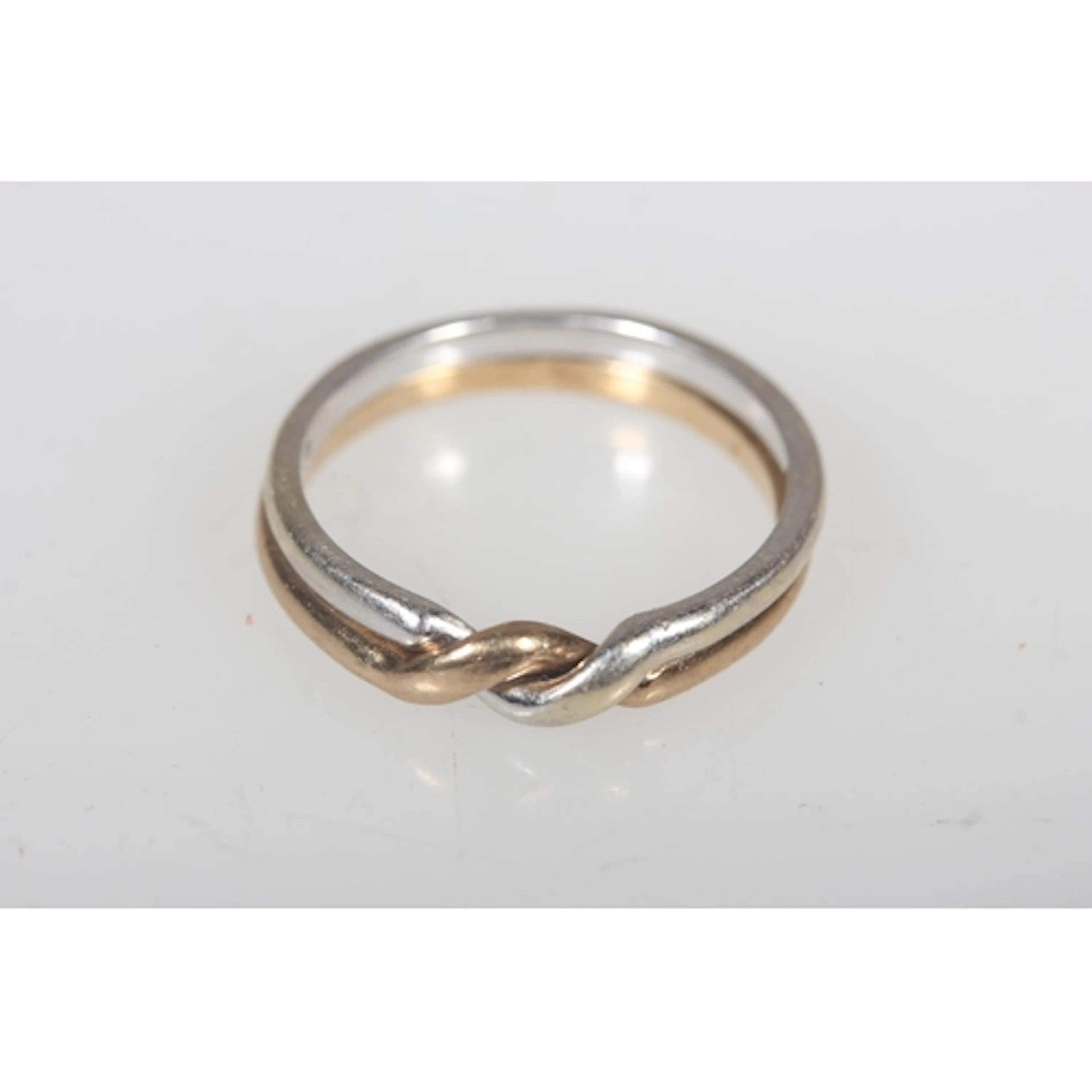 Puzzle ring formed of a gold tone band and white gold tone b...