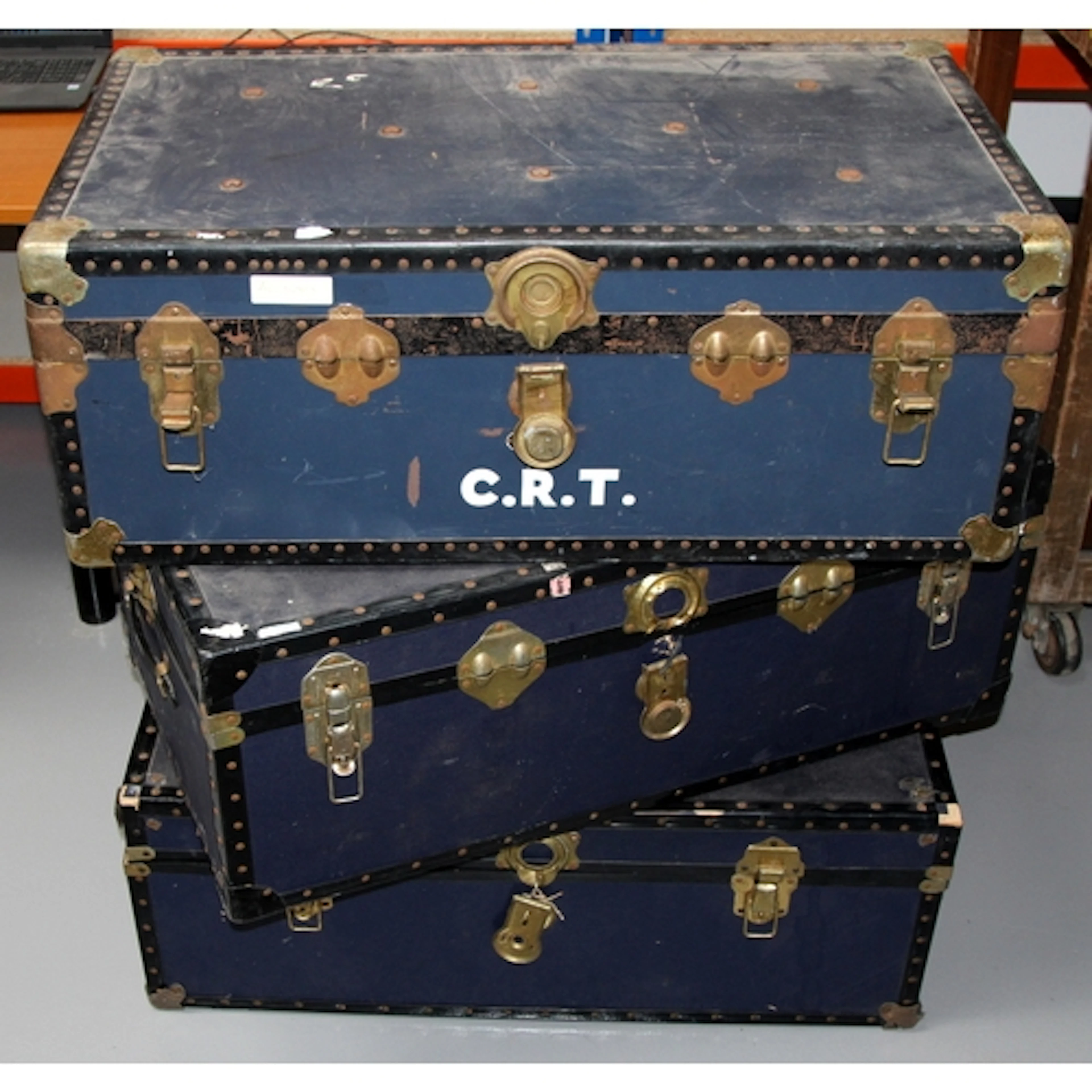 Three large flat topped steamer trunks with metal fastenings...