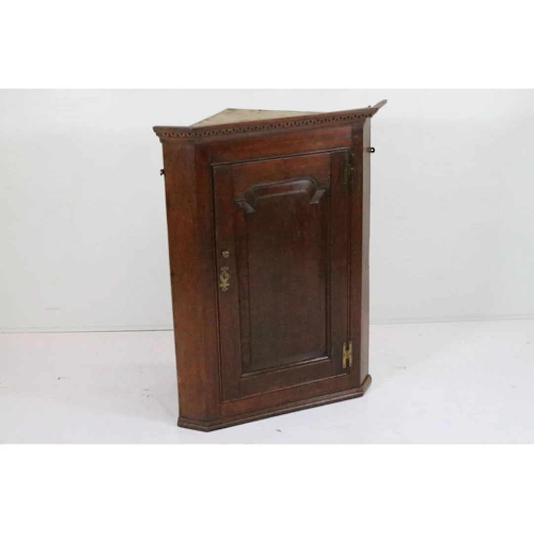 Georgian oak corner cupboard, having dentile cornice above p...