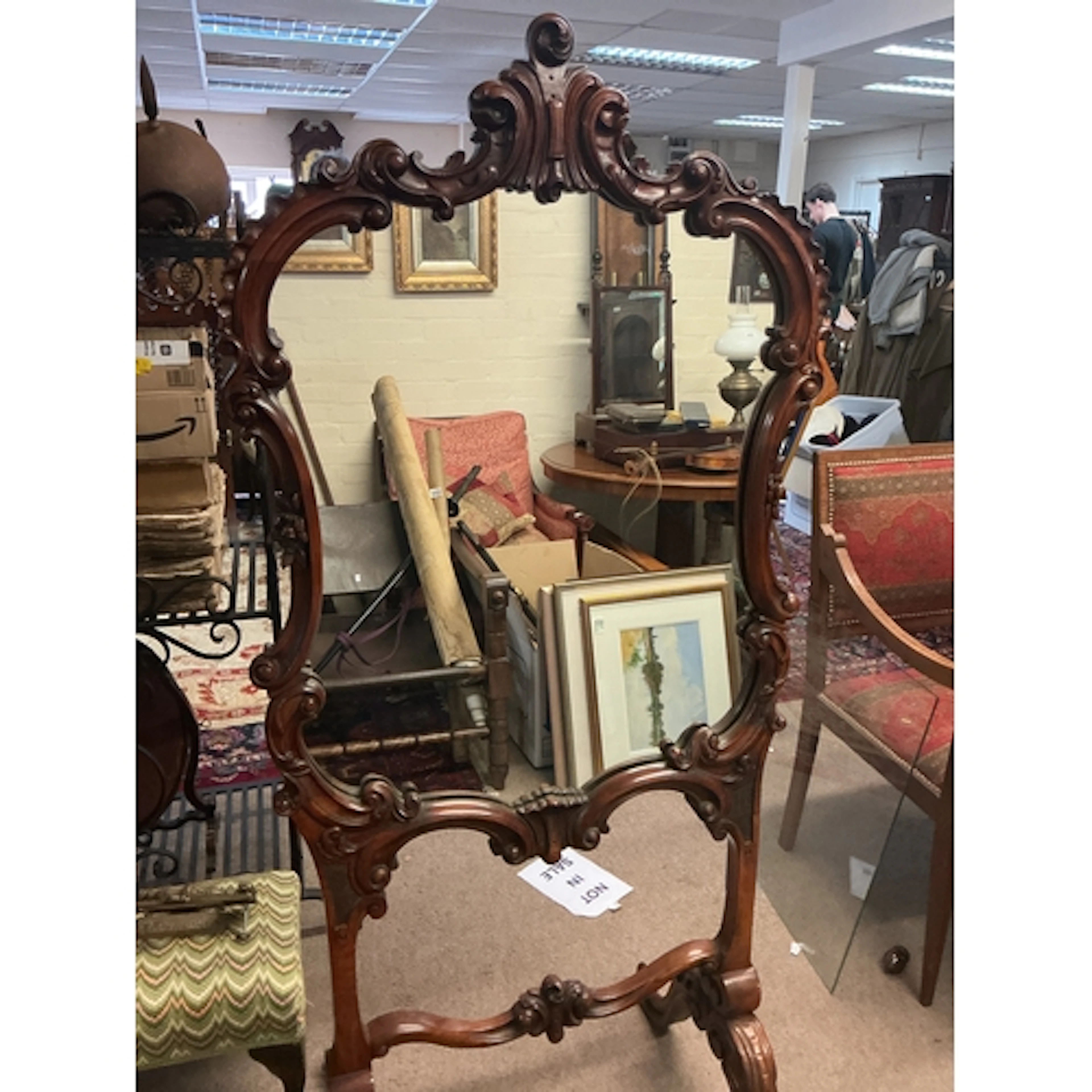 A large mirror with an ornate, hand-carved dark wood frame. ...