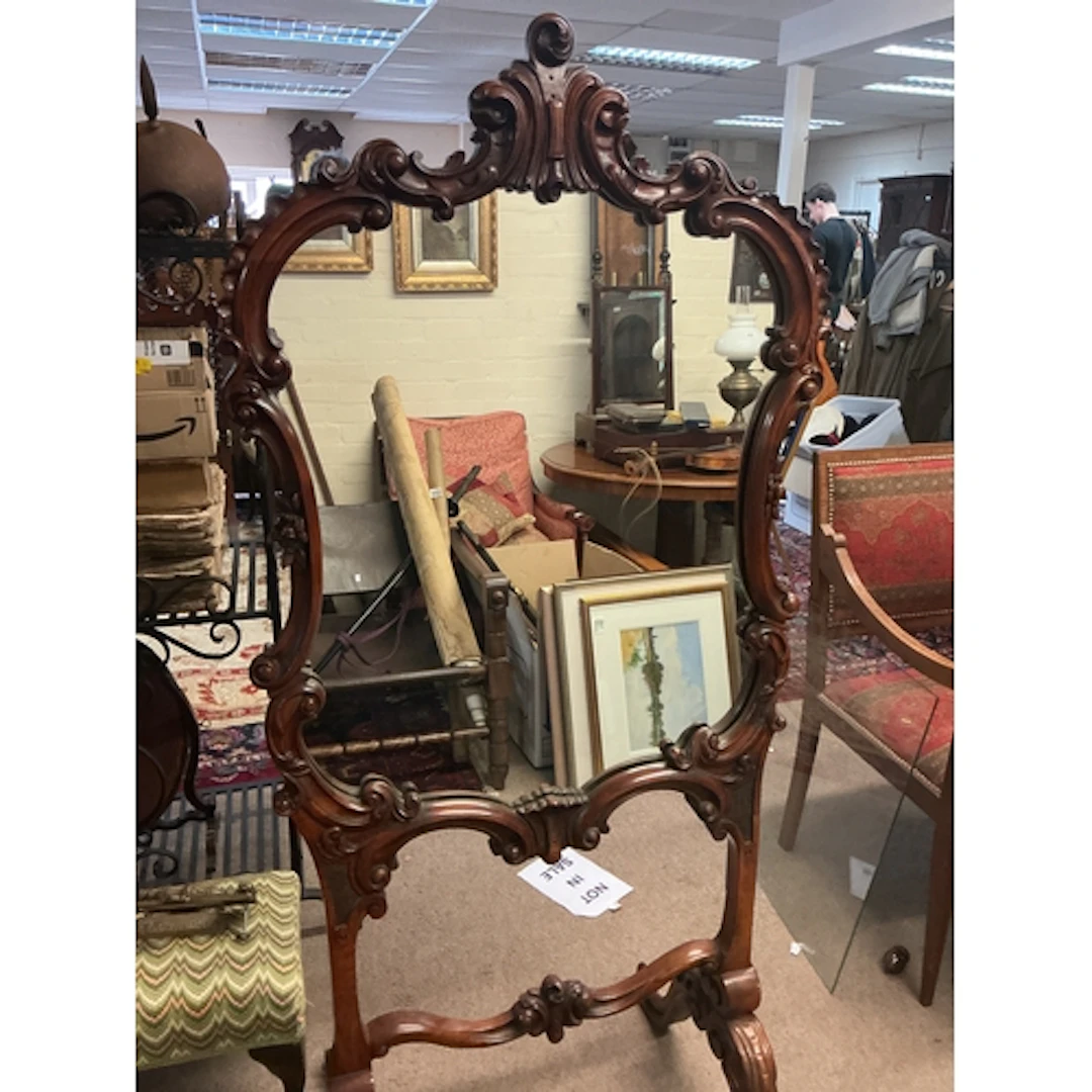 A large mirror with an ornate, hand-carved dark wood frame. ...