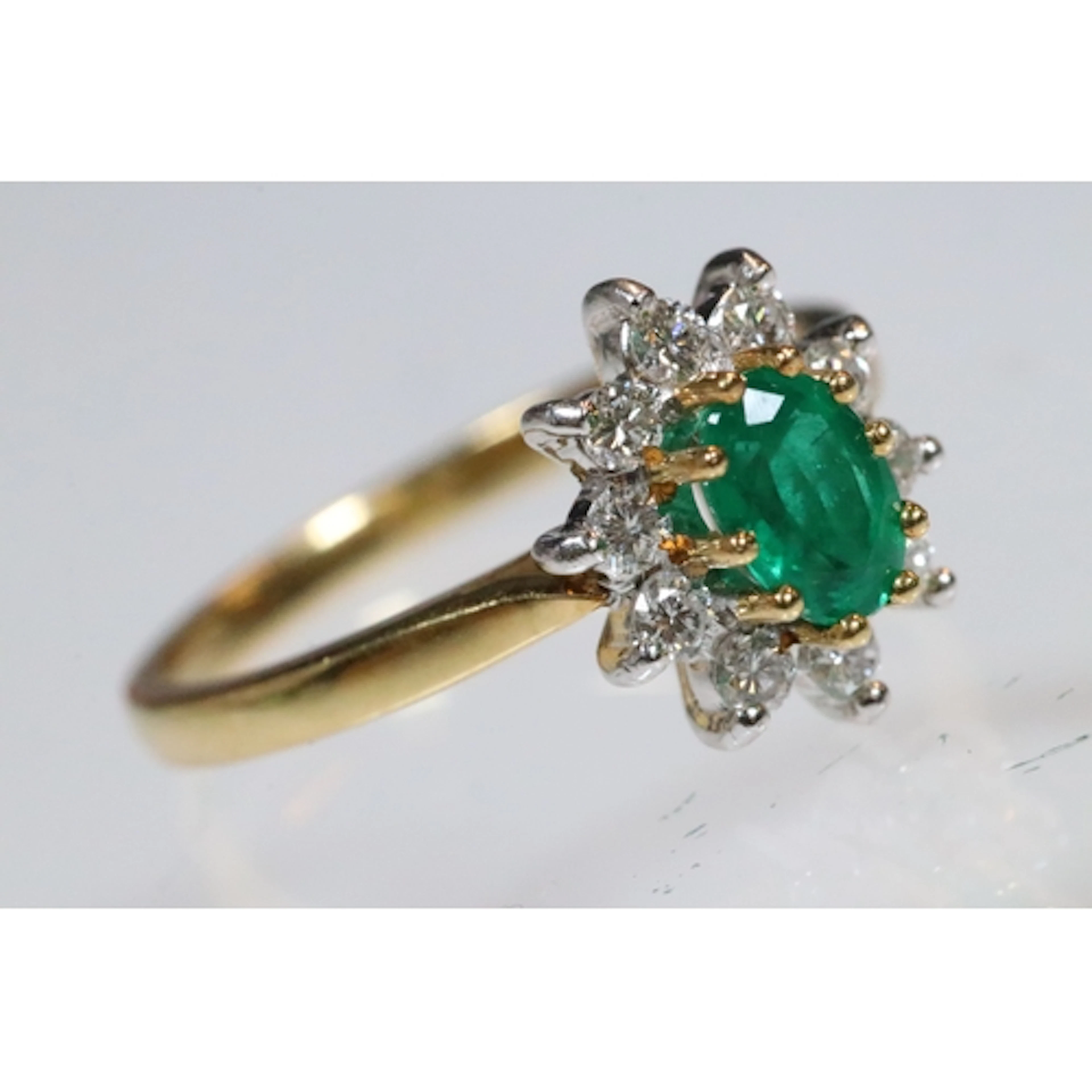 18ct gold, emerald and diamond cluster ring. The ring being ...
