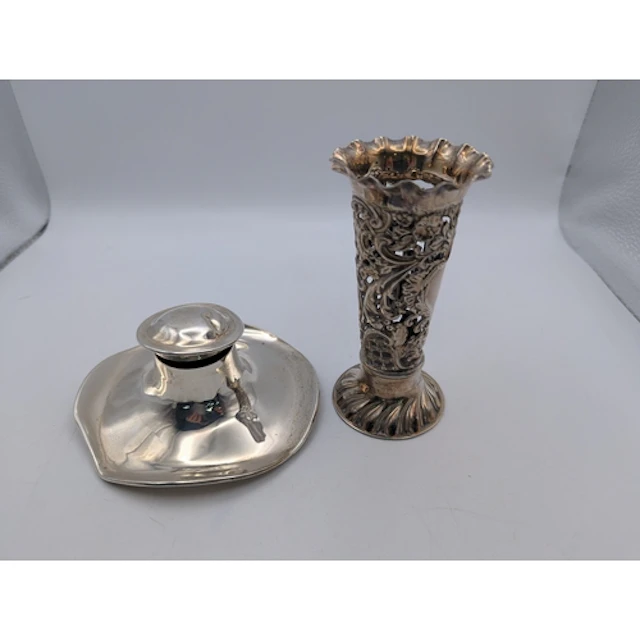 A silver vase of pierced design with a flared rim on a circu...