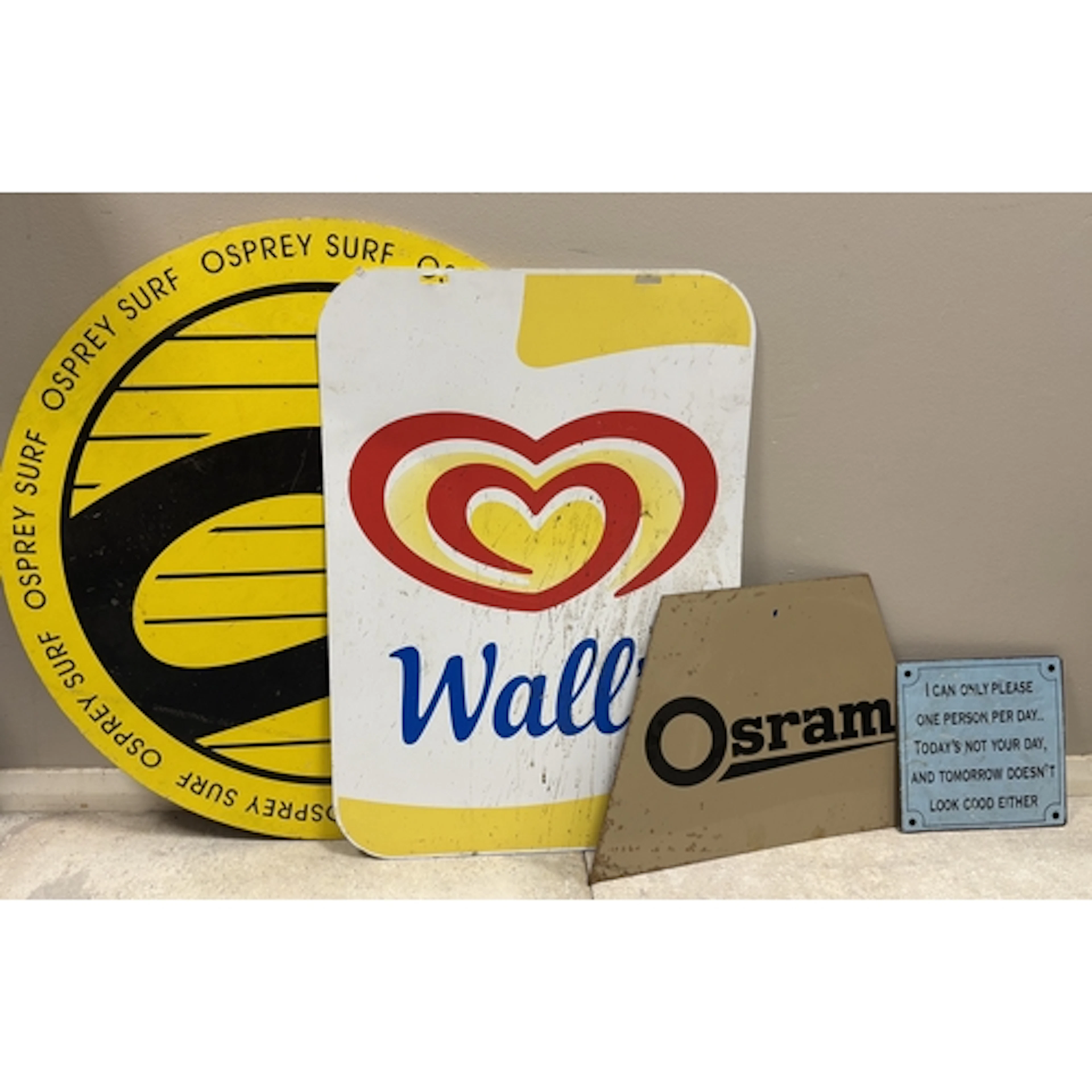 A collection of four signs including "Osprey Surf", "Wall's ...