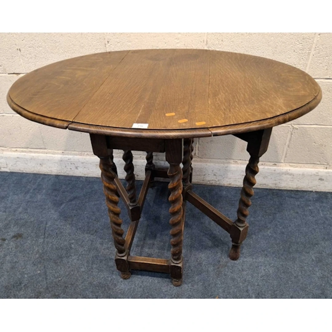 AN EARLY 20TH CENTURY OAK GATE LEG TABLE, raised on barley t...
