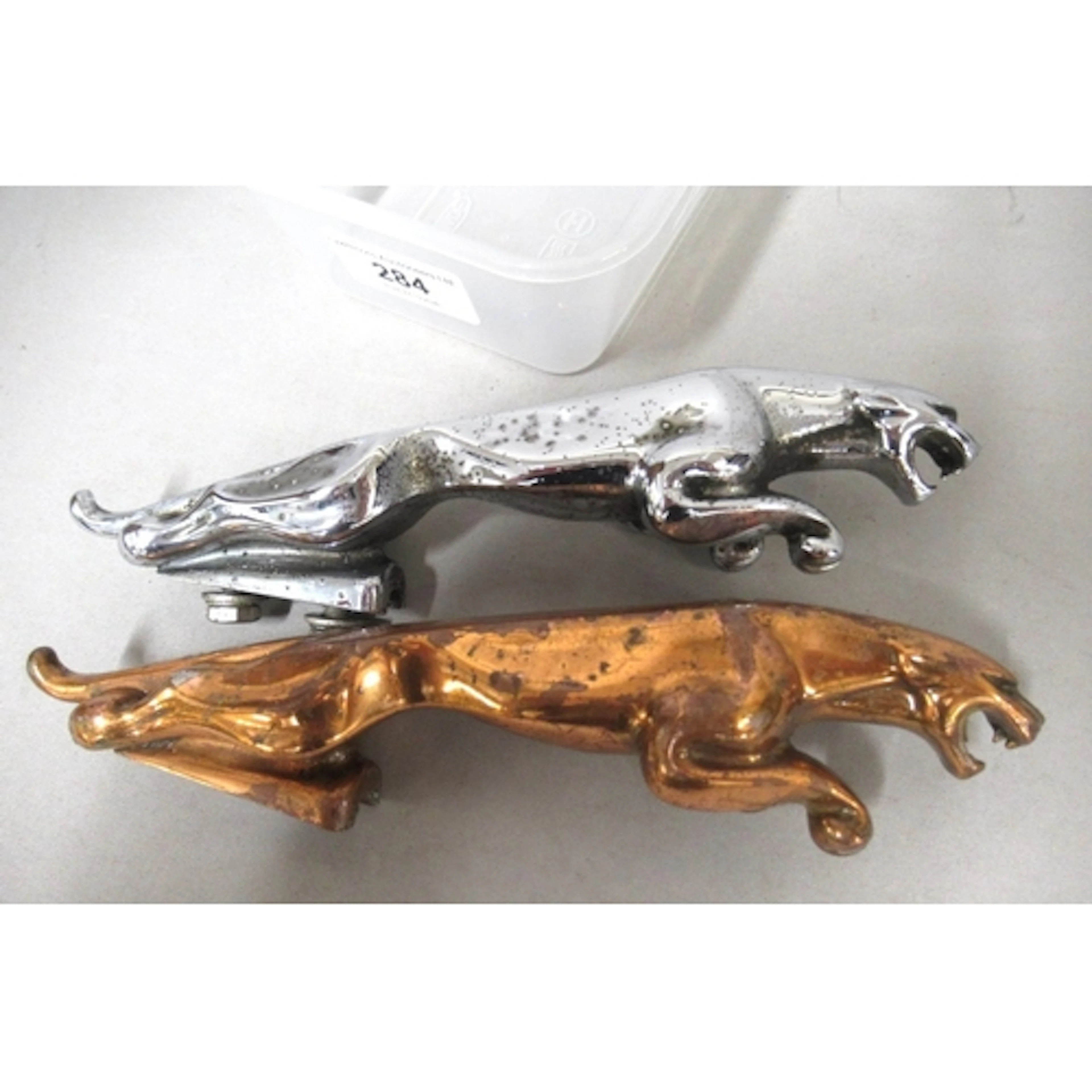 Two Jaguar car mascots, in copper and chrome