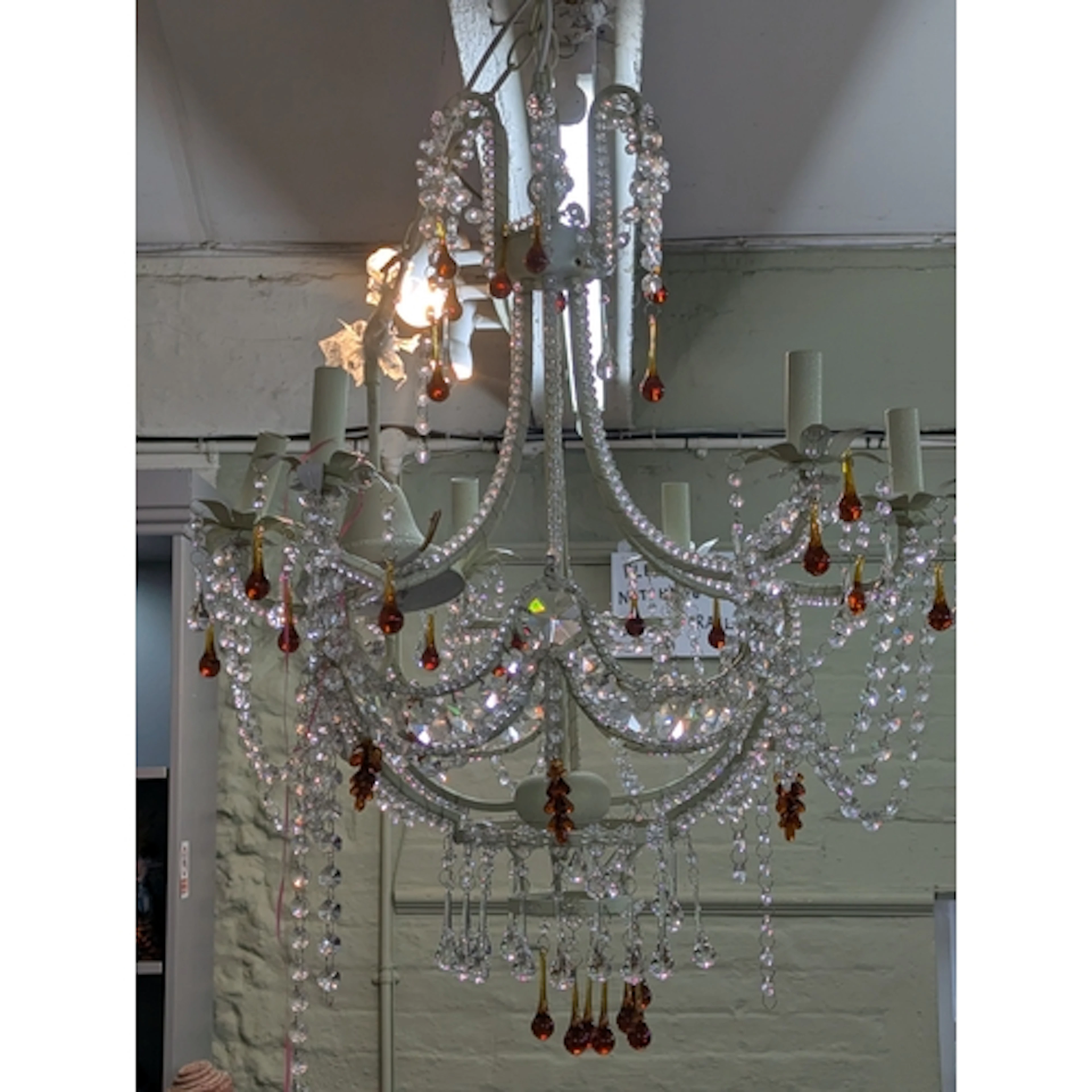 A modern cream cage chandelier featuring amber coloured tear...