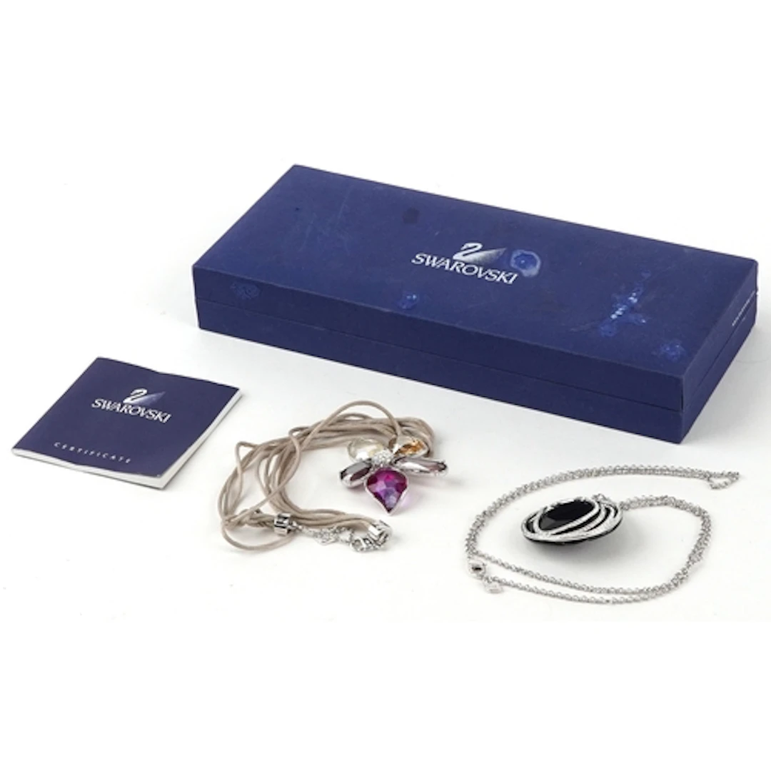 Two Swarovski coloured crystal pendants on chains, the large...