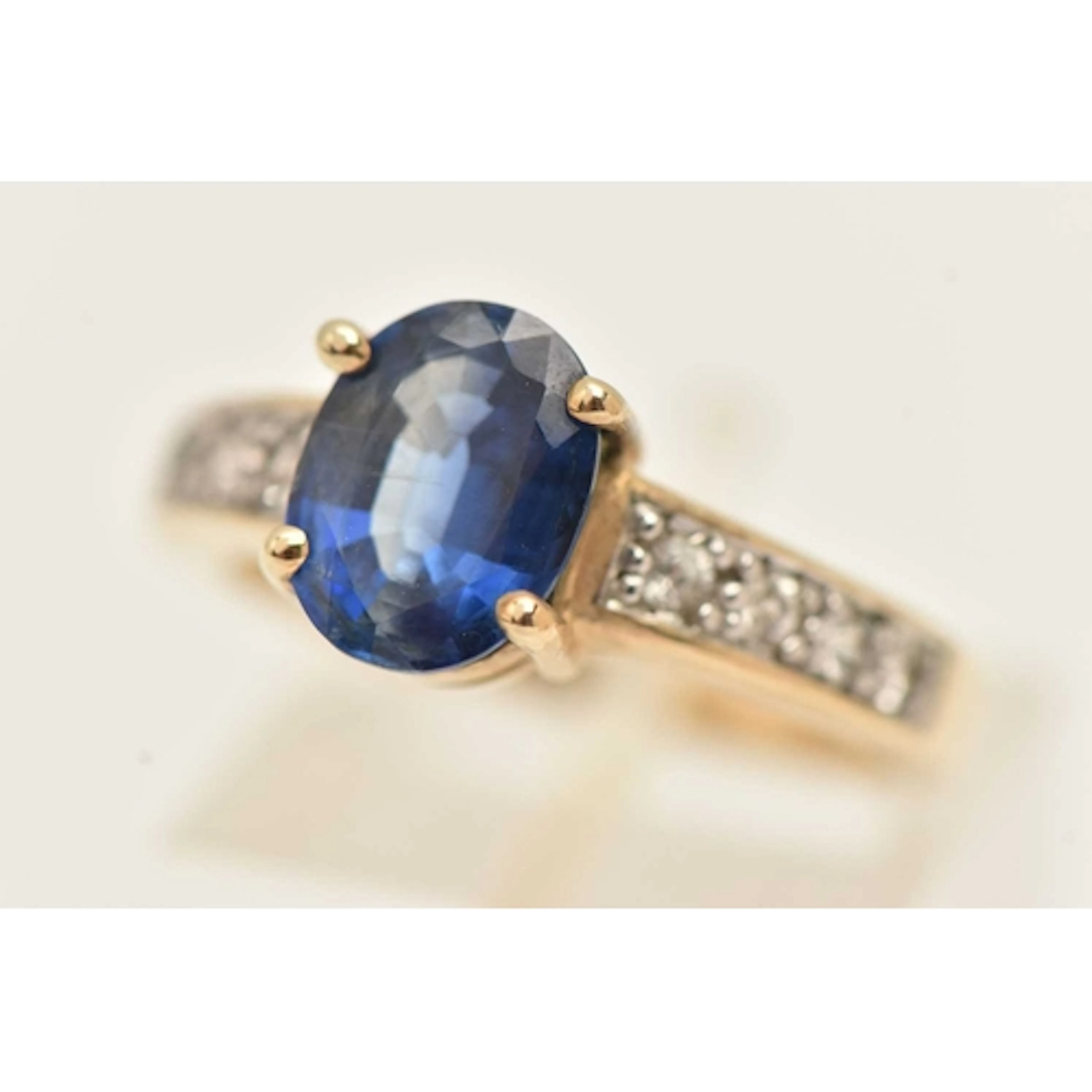 A 9CT GOLD GEM SET RING, four claw set with an oval cut blue...