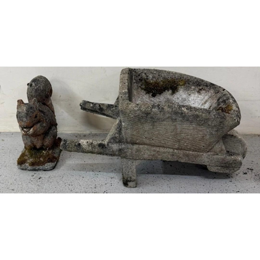 A concrete garden ornament of a squirrel and a wheelbarrow...
