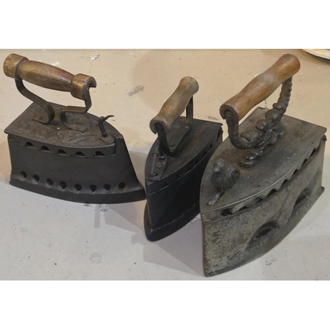 Three vintage cast iron irons, one with patter, one with coc...
