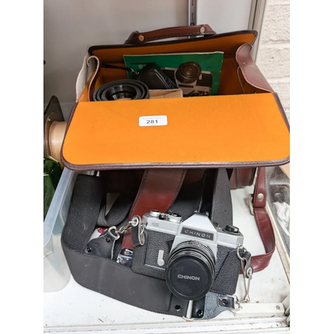 A vintage Chinon CS camera and accessories within a brown le...