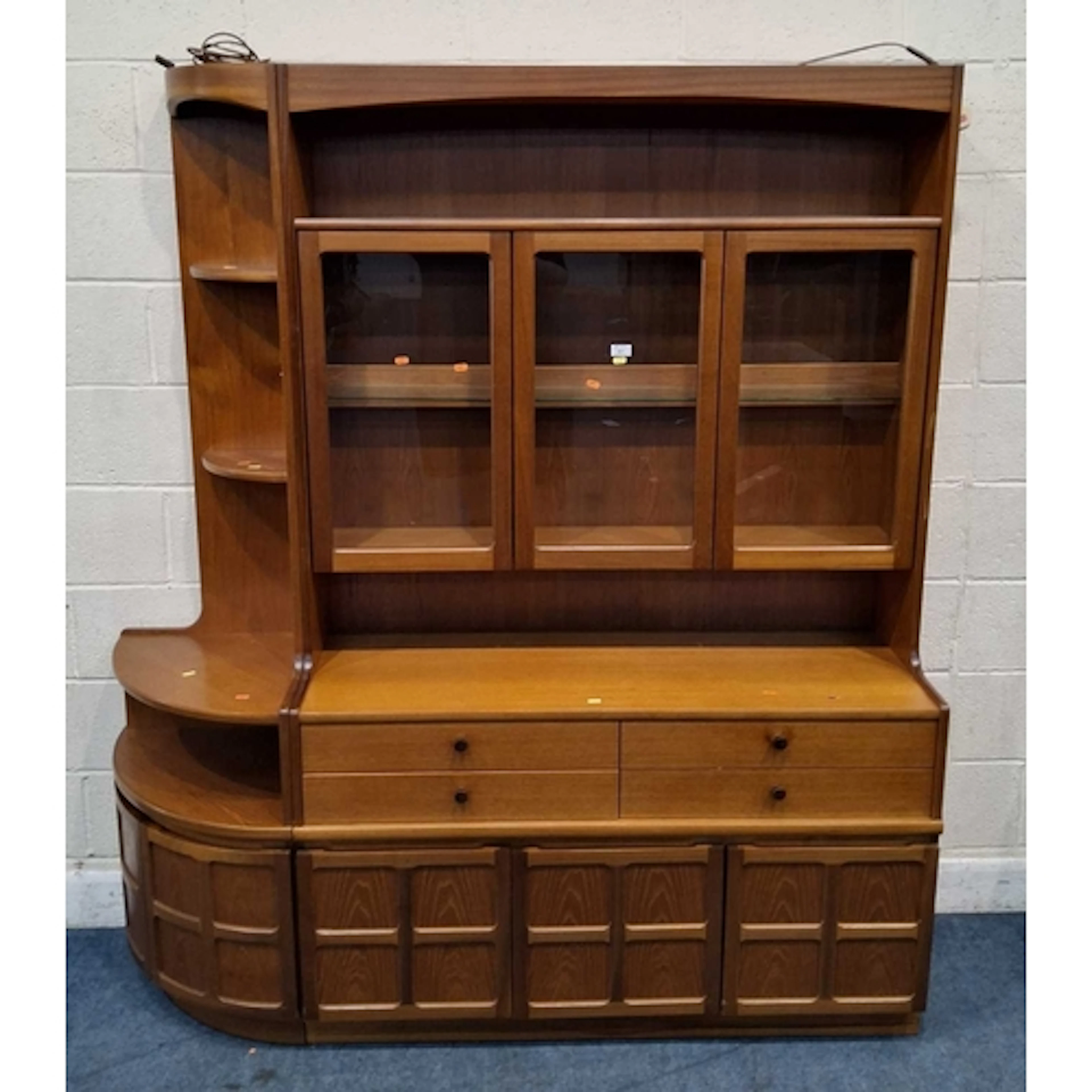 PARKER KNOLL, A MID-CENTURY TEAK WALL UNIT, the three glass ...