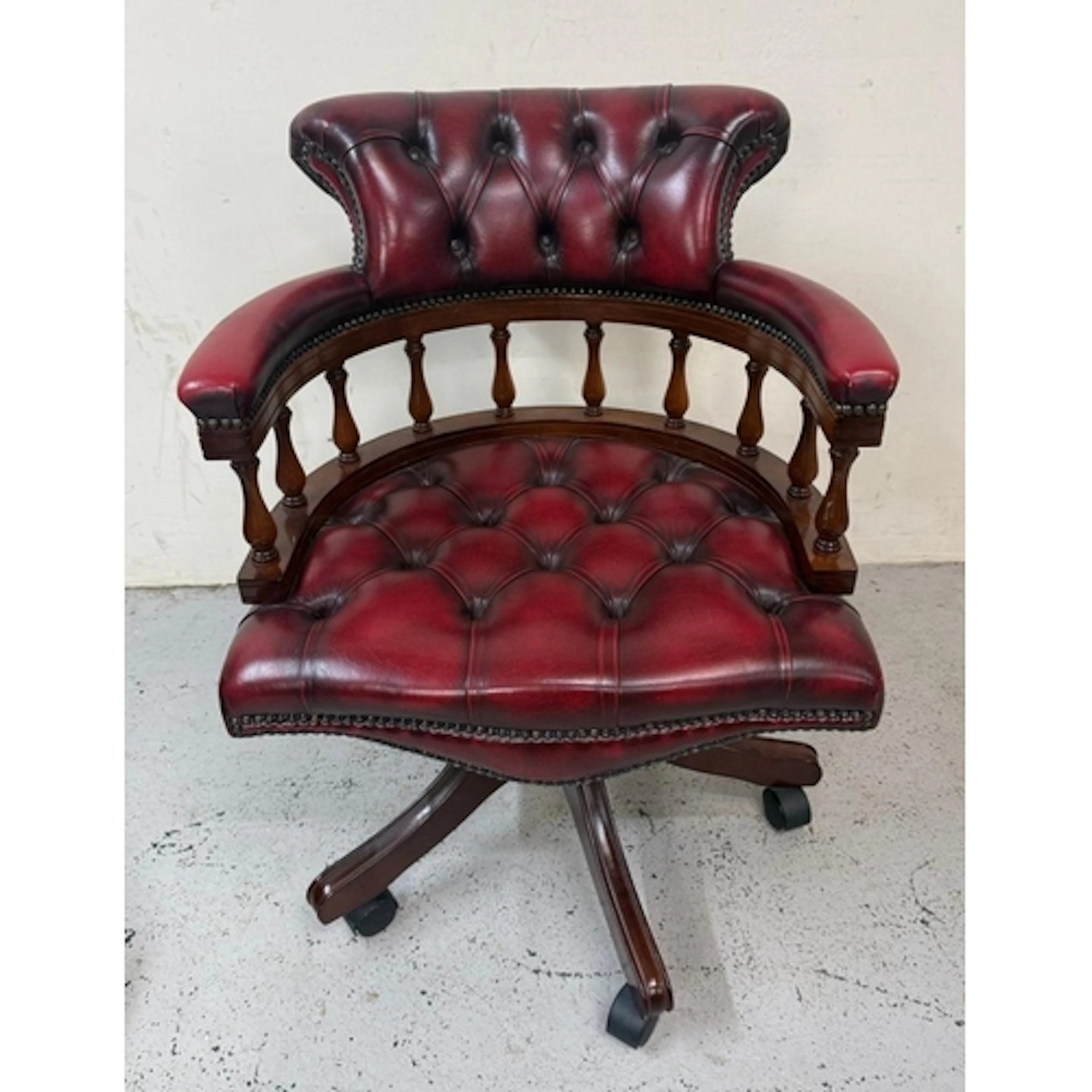 A red leather button tufted captains chair.