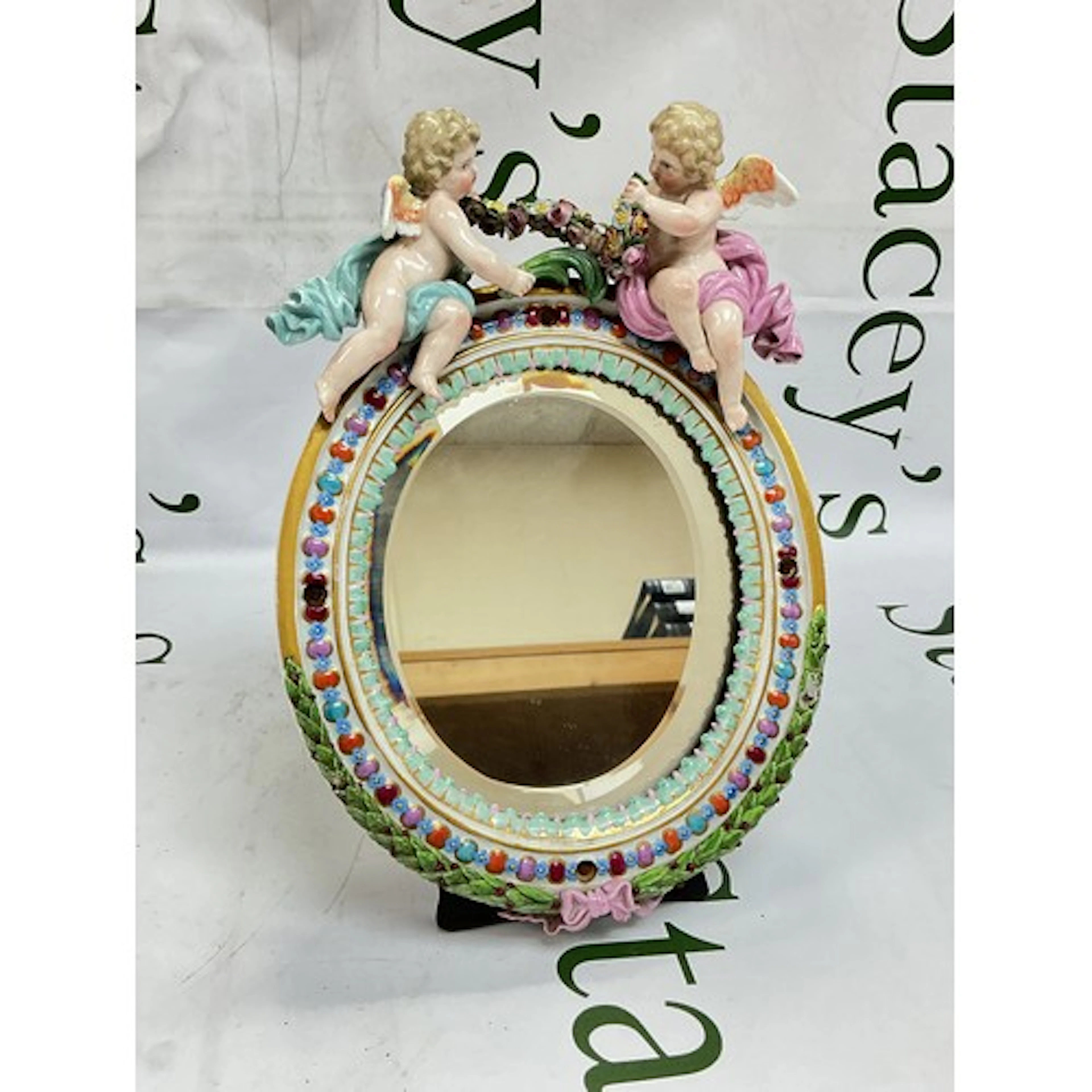 A Meissen table mirror of oval shape, surmounted by two cher...