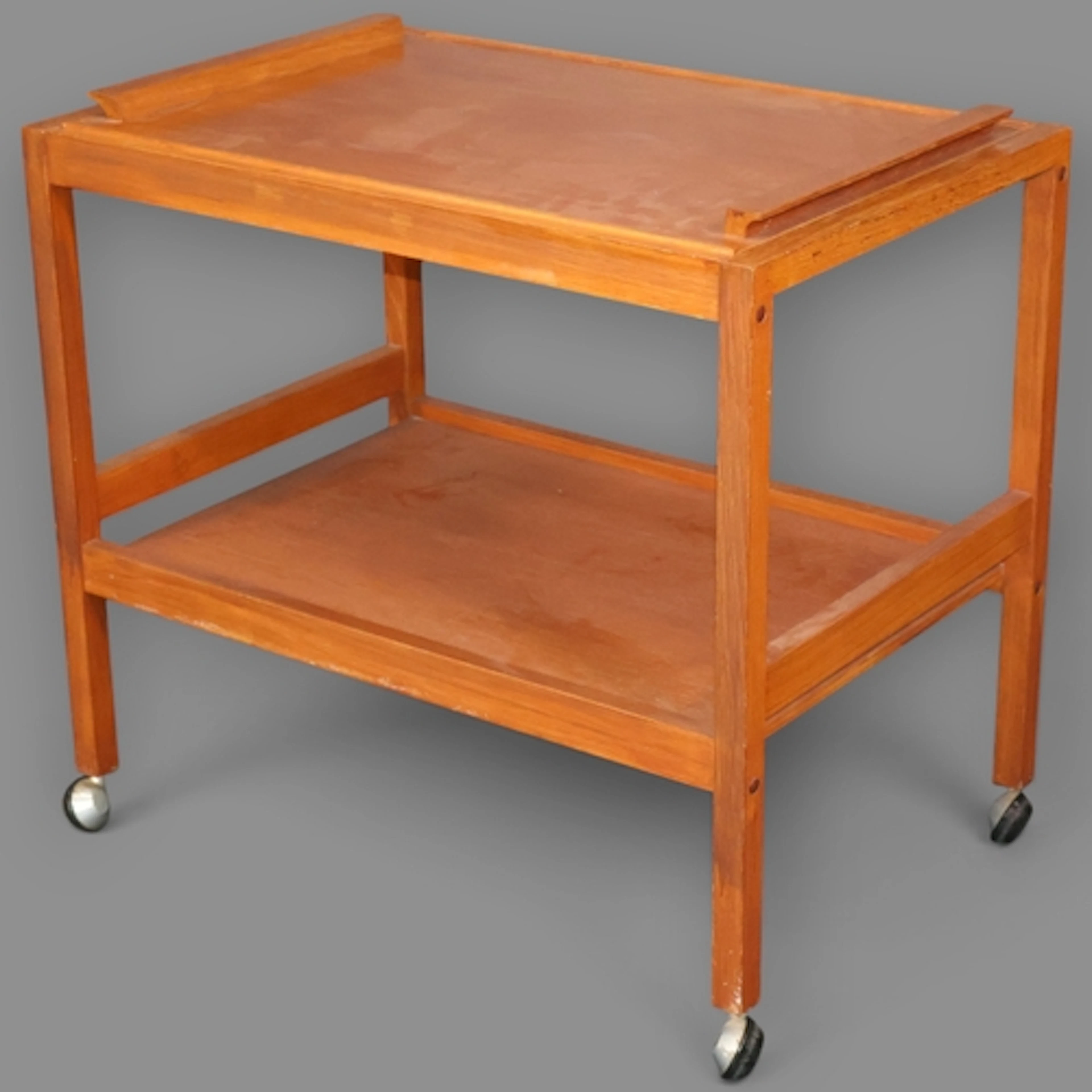A vintage Danish two tier teak drinks trolley on castors wit...