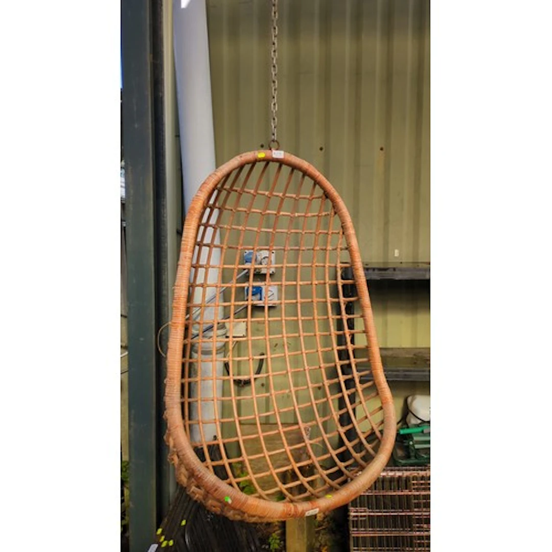 Rattan hanging egg chair suspended by a metal chain.