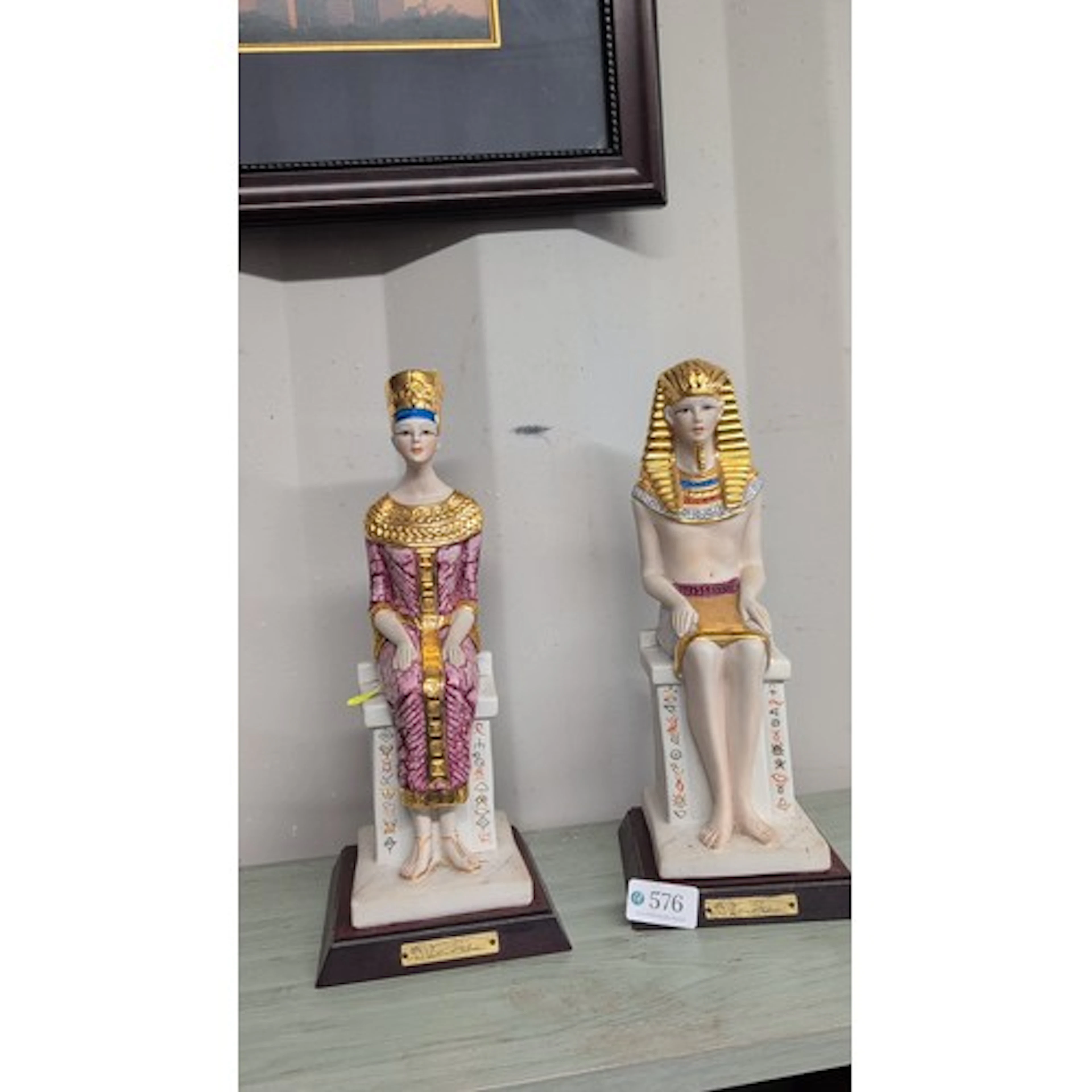 A pair of Egyptian Revival glazed ceramic seated figures on ...