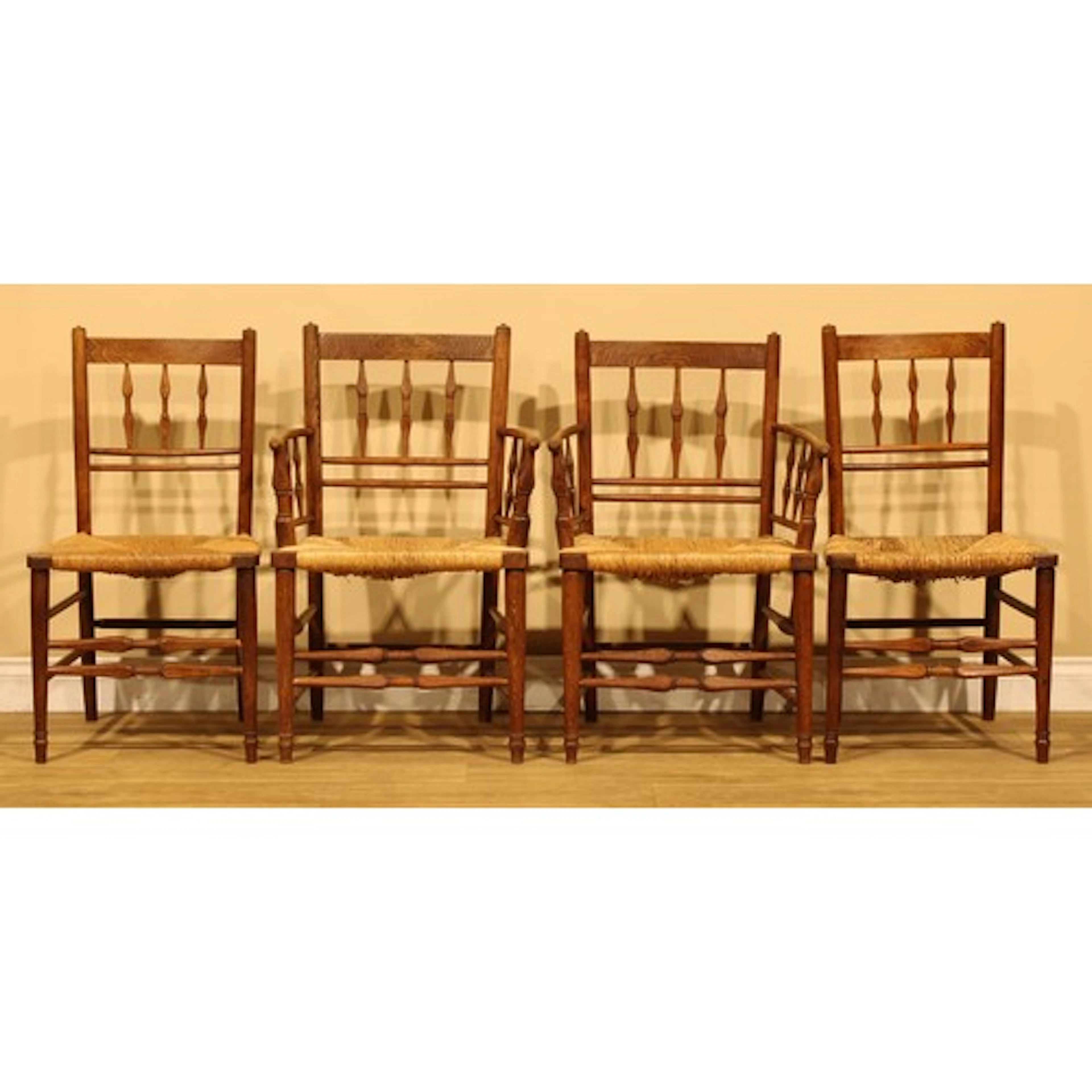 A set of four Arts & Crafts vernacular oak dining chairs, po...