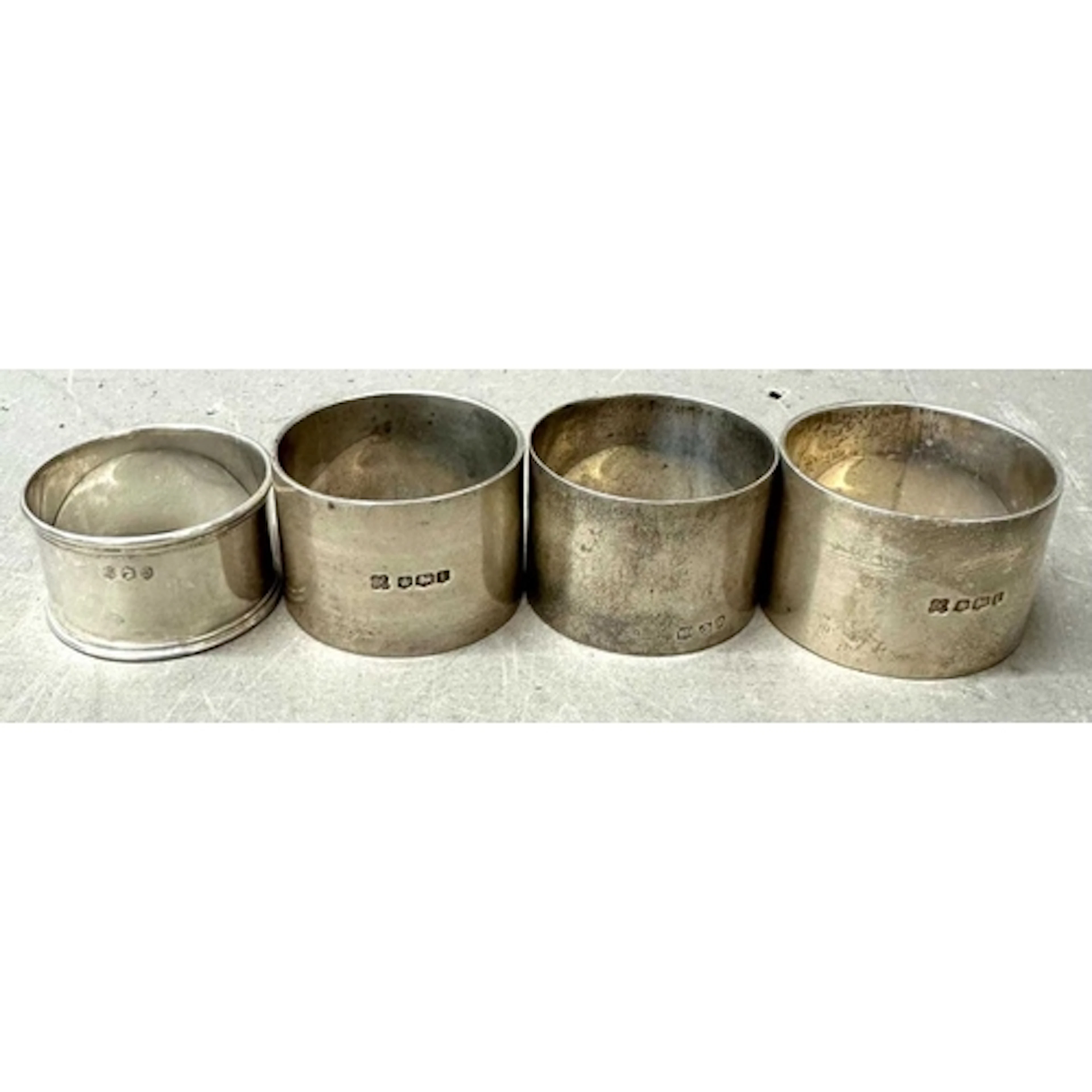 Four sterling silver napkin rings with various hallmarks, tw...
