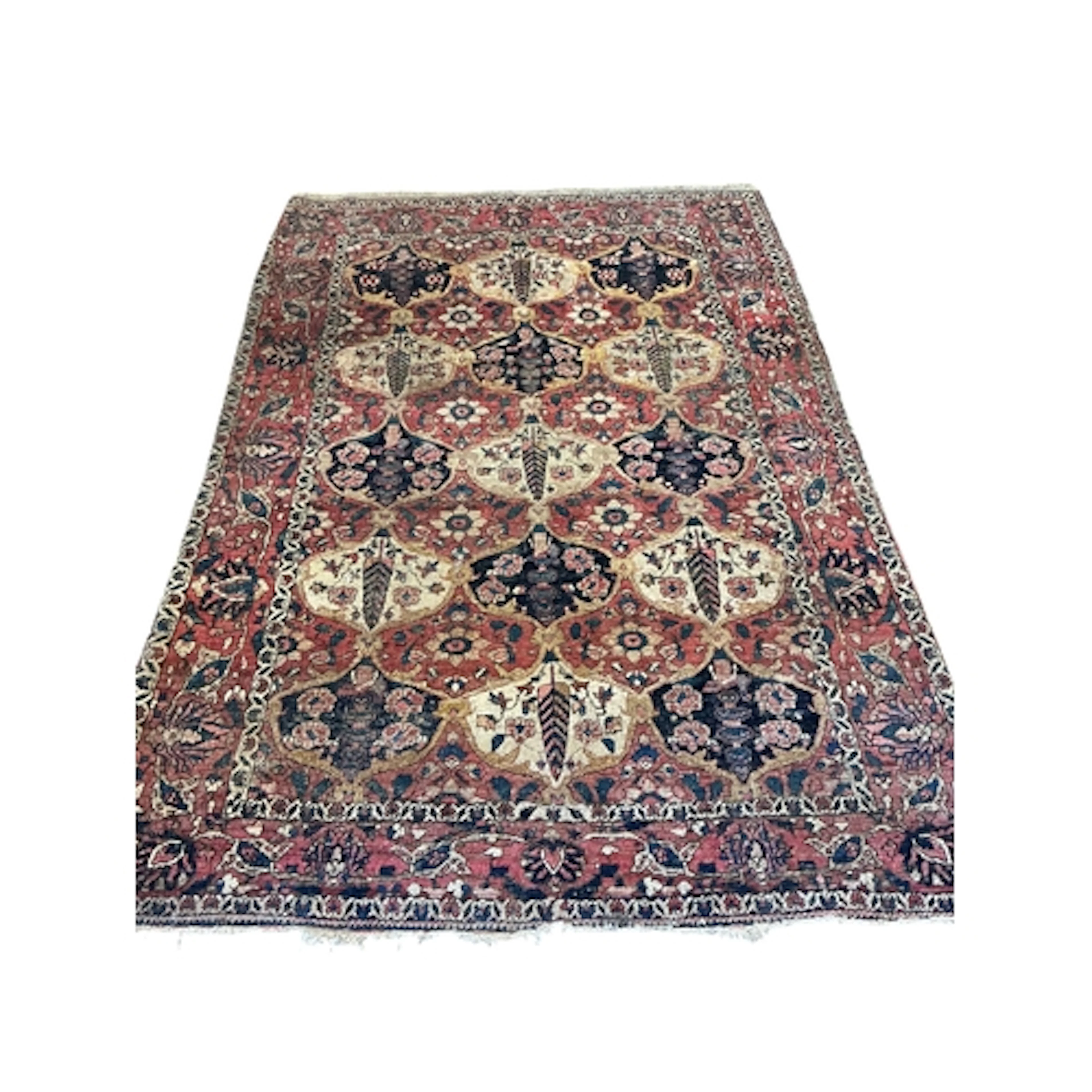 An antique Bakhtiari red ground rug woven with stylized flor...