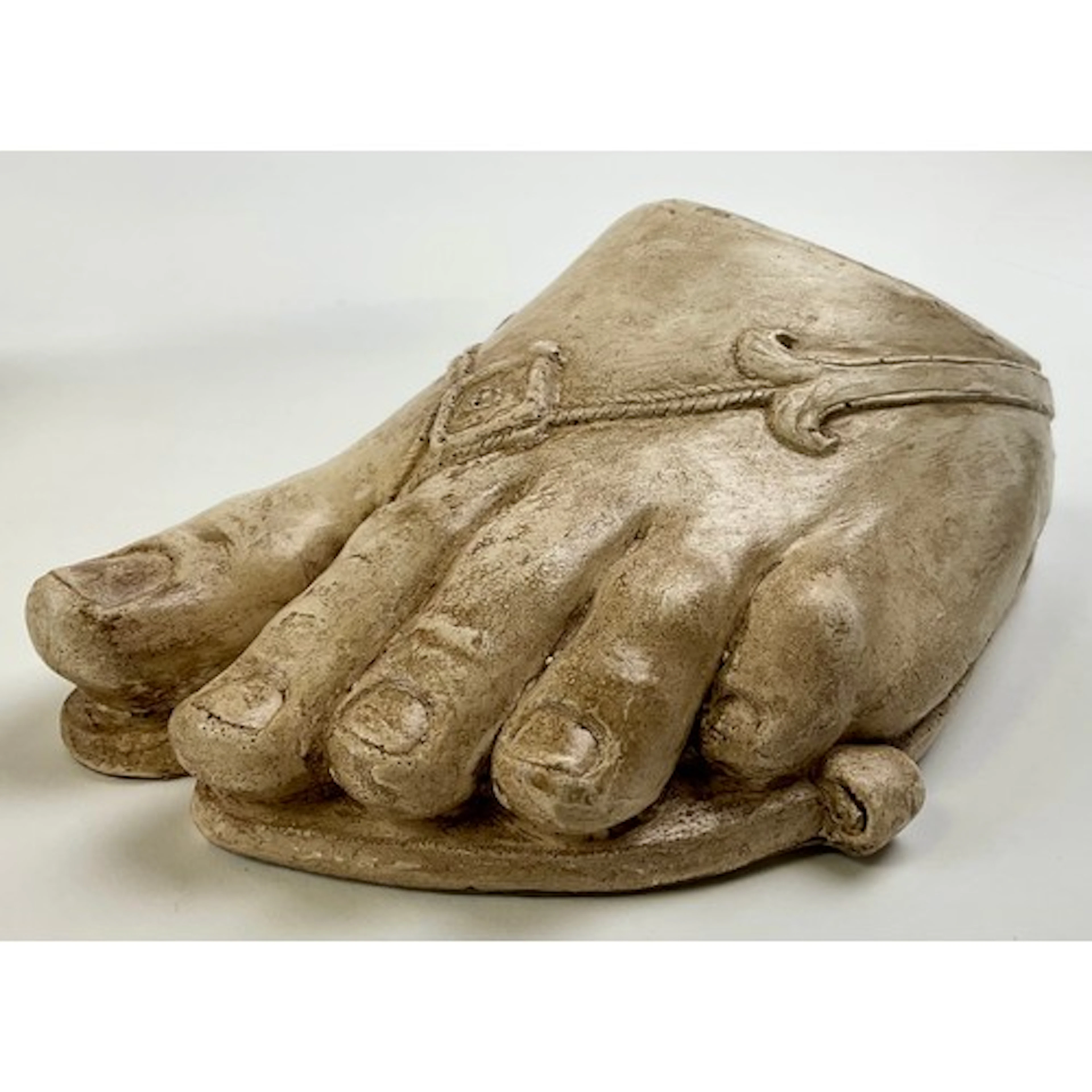 A museum type plaster cast, of a foot wearing a sandal, afte...