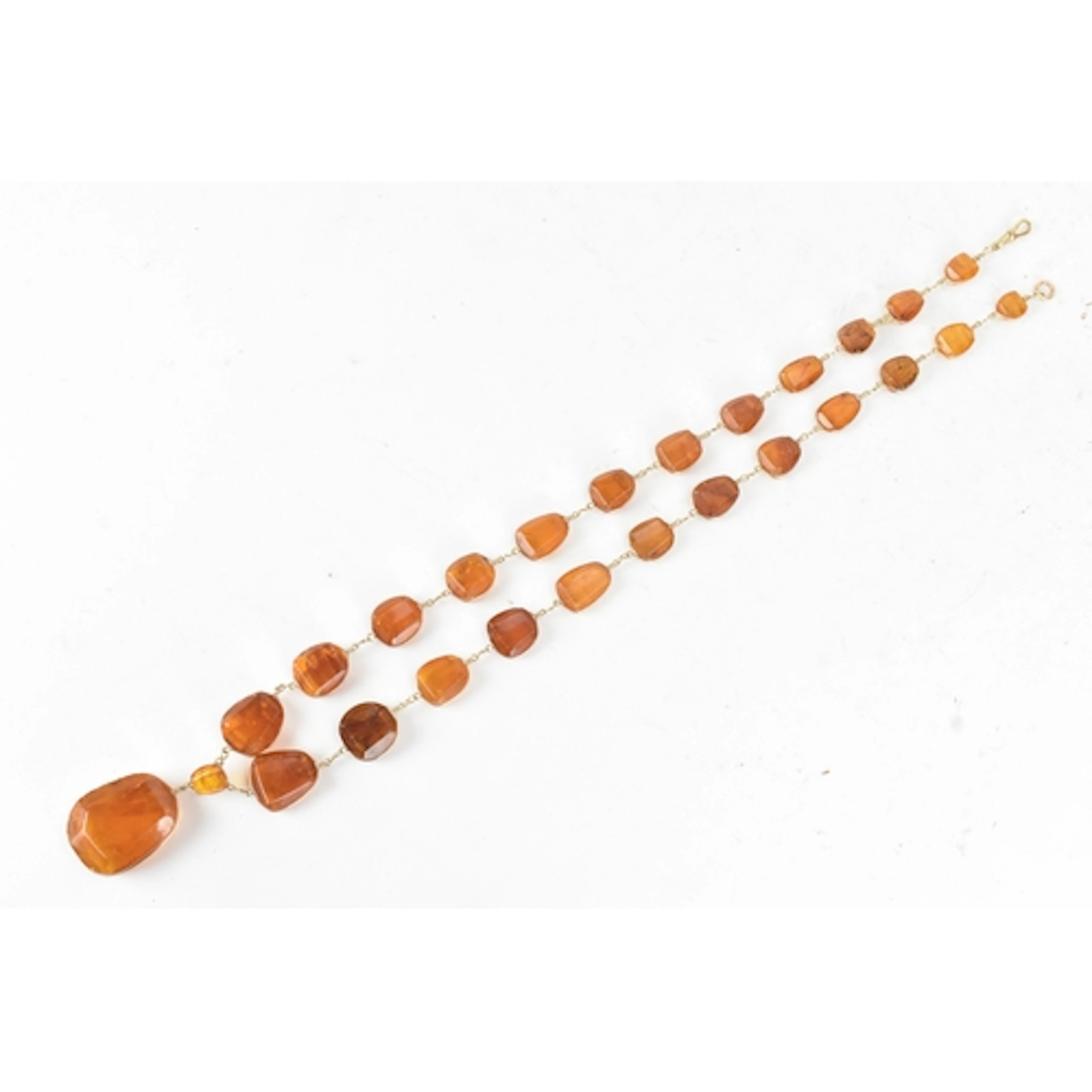 A graduated amber and gold-plated necklace, formed from a se...