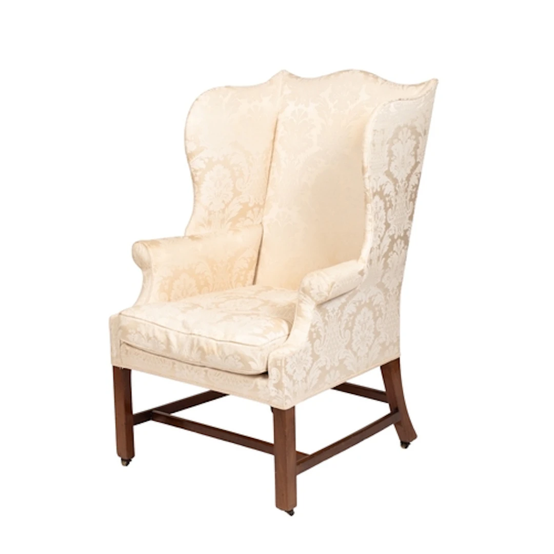 An upholstered wing armchair in George III style, early 20th...