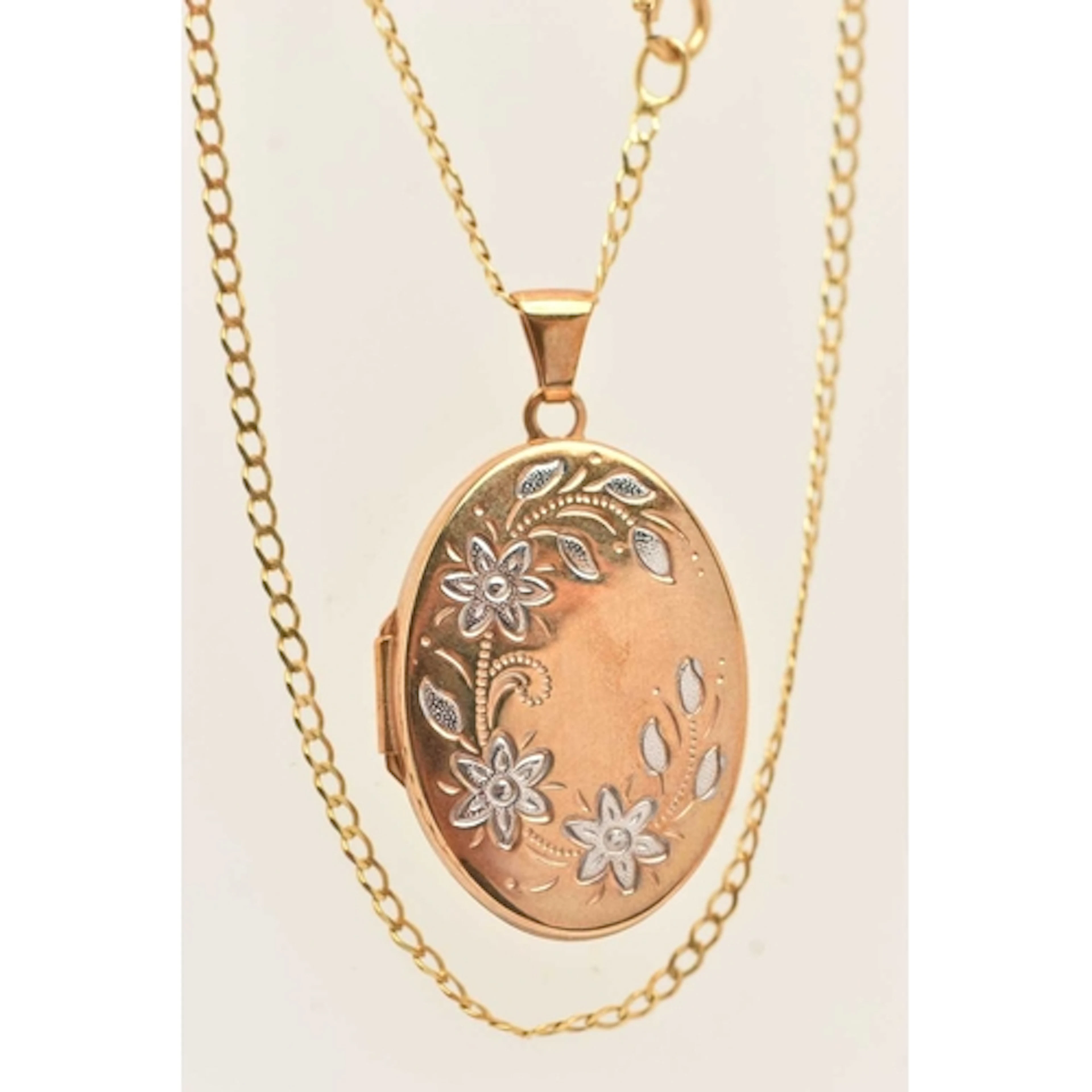 A 9CT GOLD OVAL LOCKET PENDANT WITH CHAIN, decorated with fl...