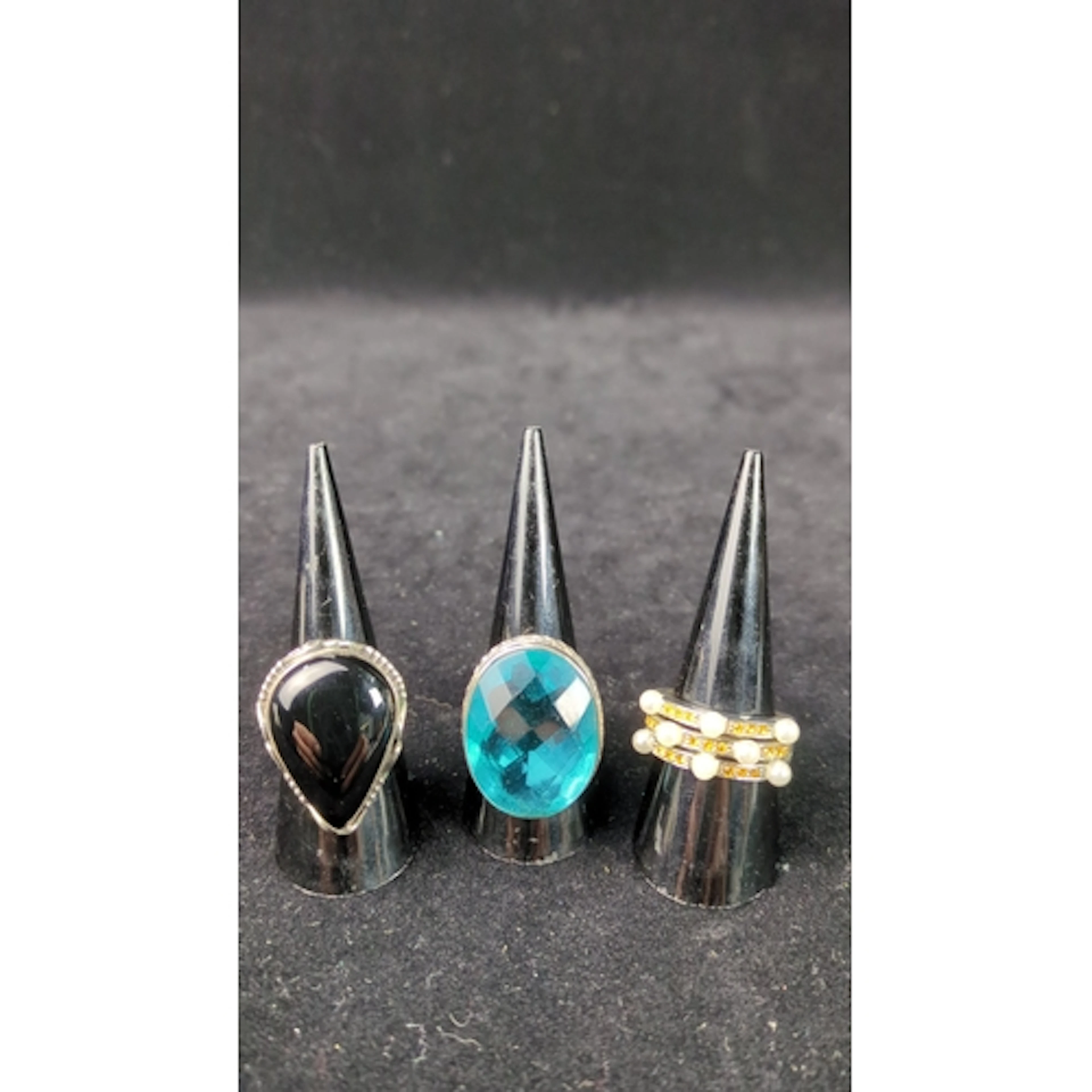 Three silver dress rings: a pear-shaped black cabochon in a ...