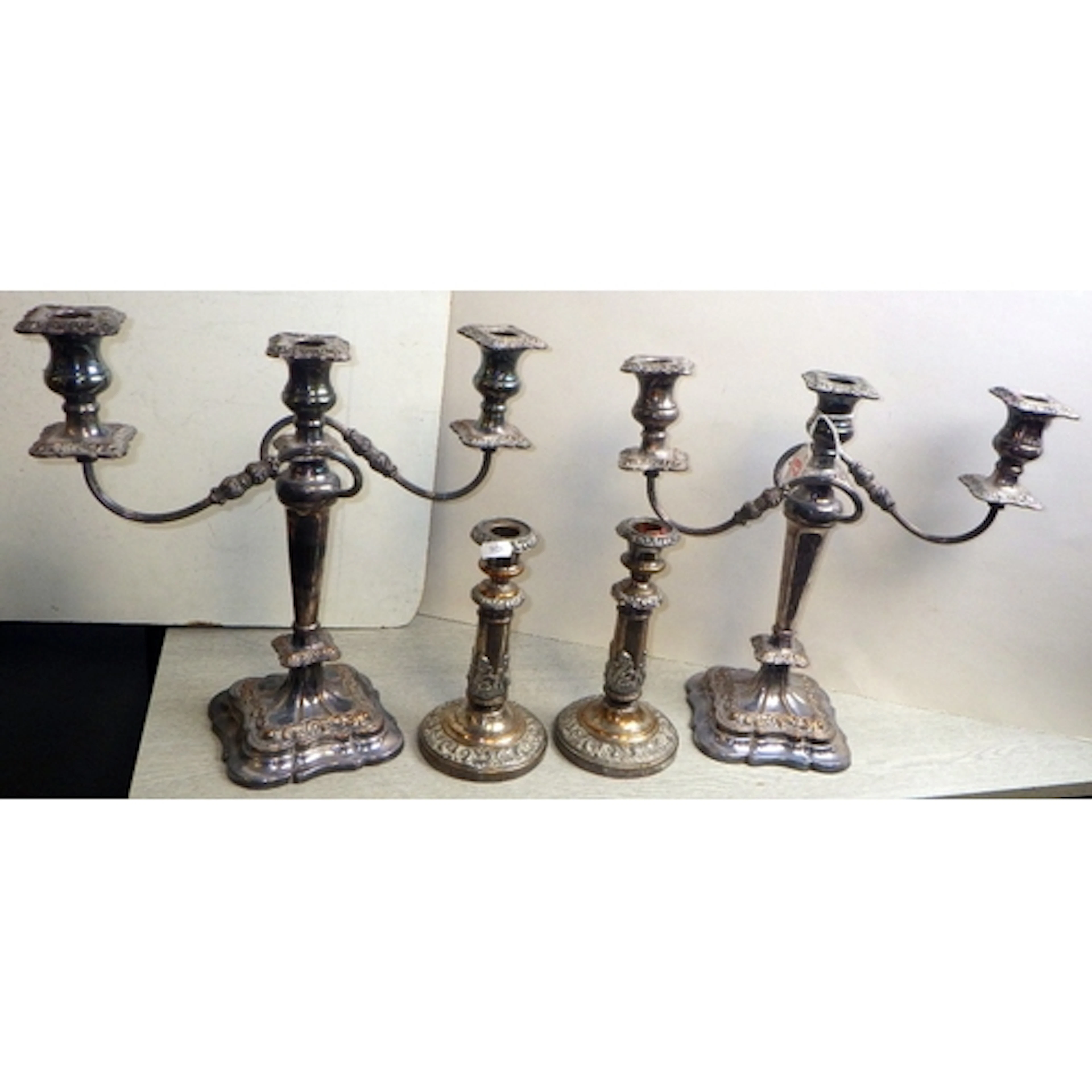 A pair of worn silver plated candelabras and a pair of candl...