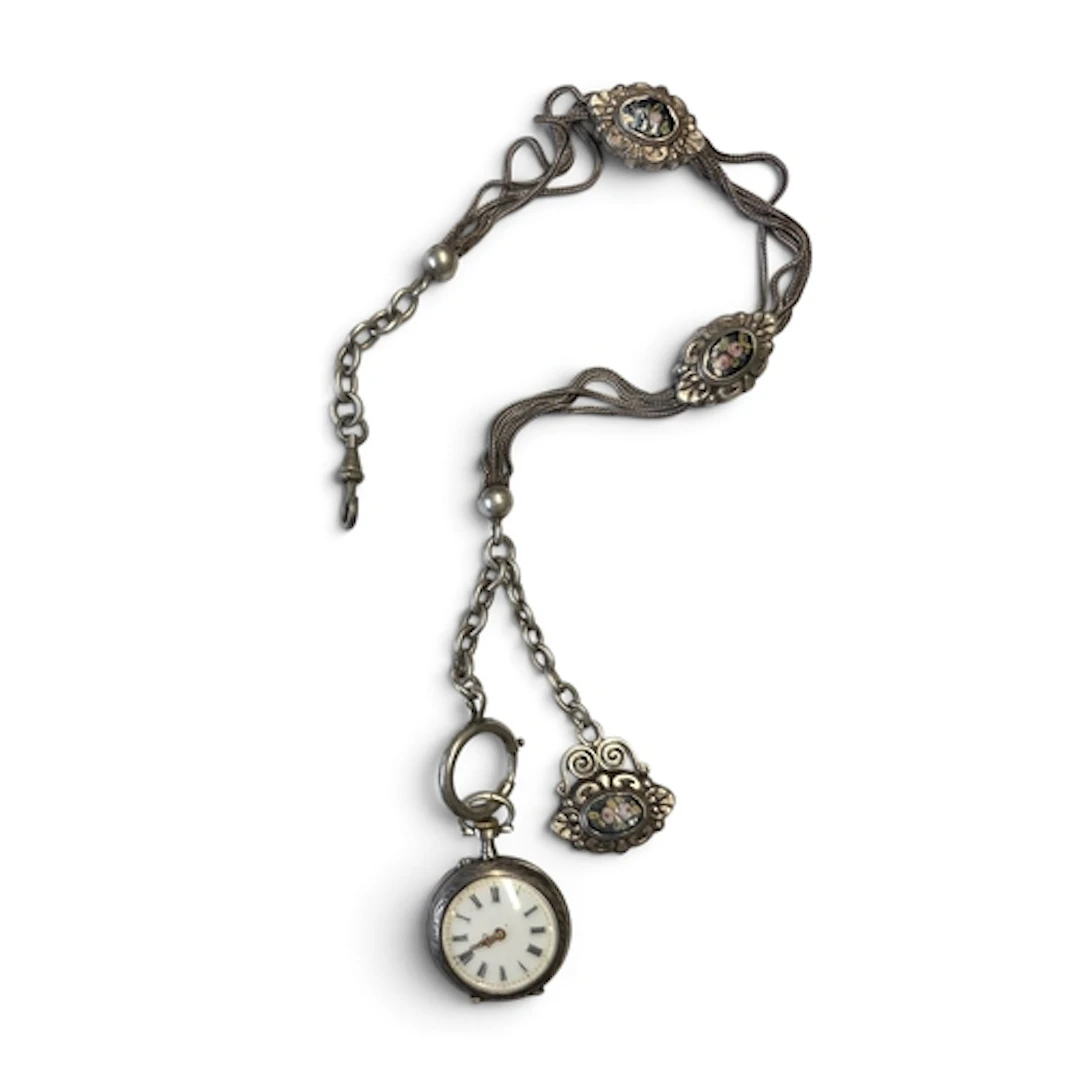 A Silver pocket watch with a silver chain, featuring silver ...