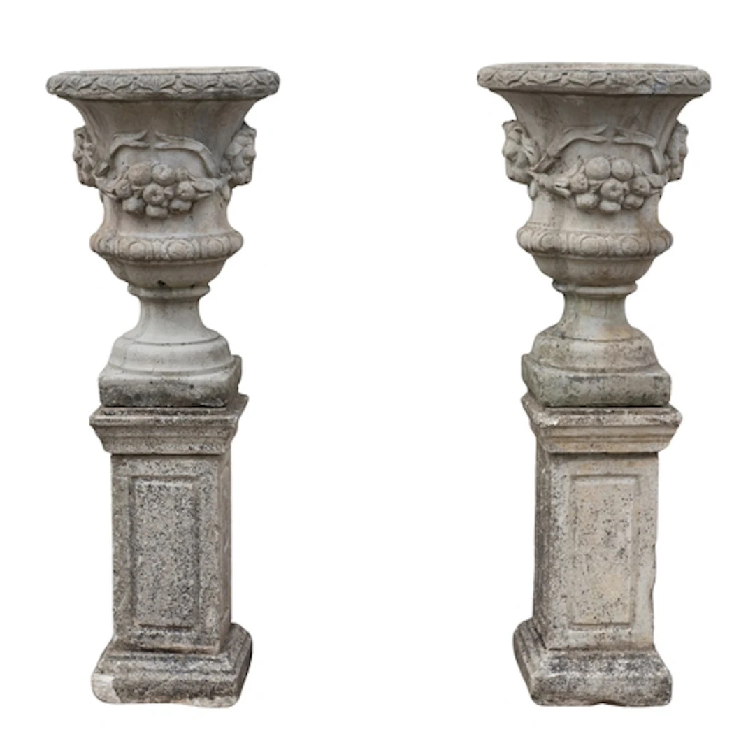 A pair of stone composition garden urns on plinths, 20th cen...