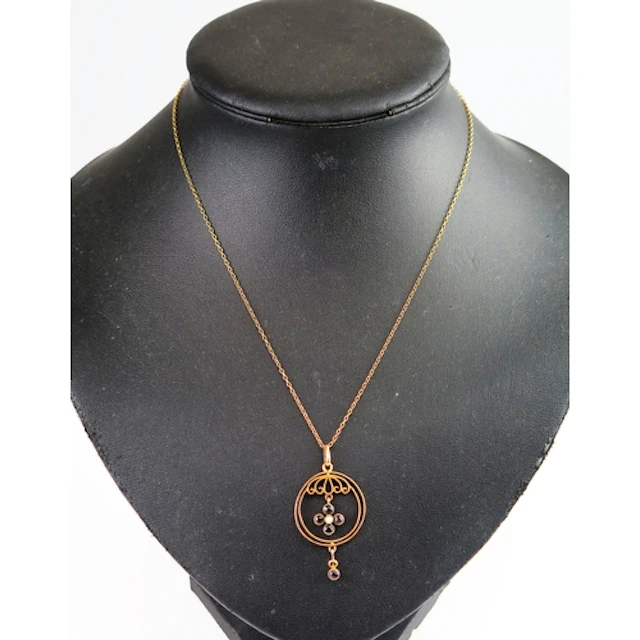 A garnet and seed pearl pendant in a 9ct yellow gold setting...