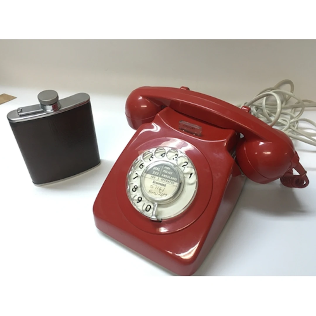 A vintage red telephone and a hip flask
