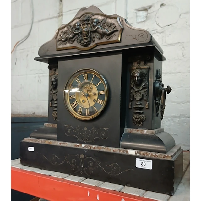 A slate clock with marble inlay and decorated with carved mi...