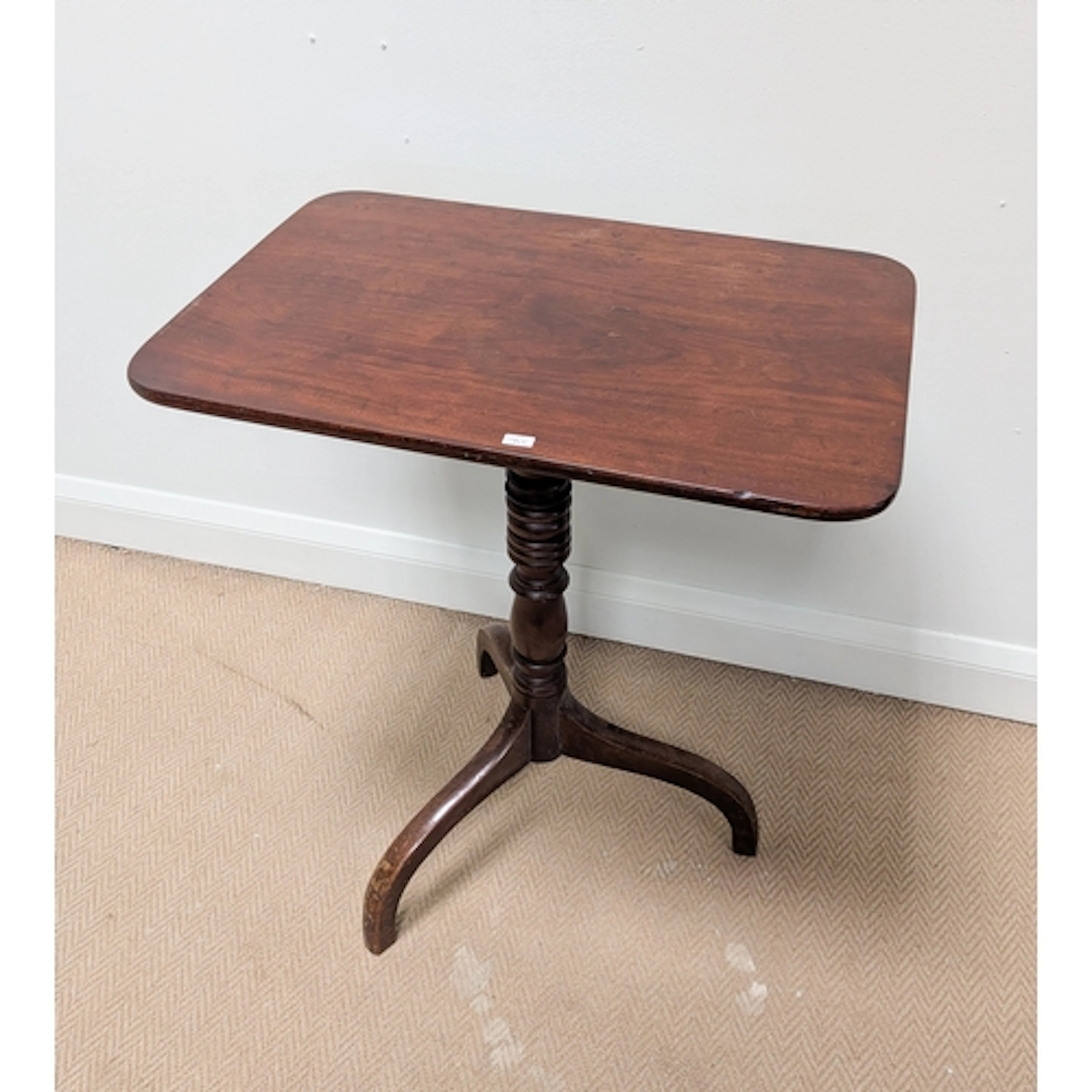 A antique mahogany snap top tripod table. Top measures 24" x...