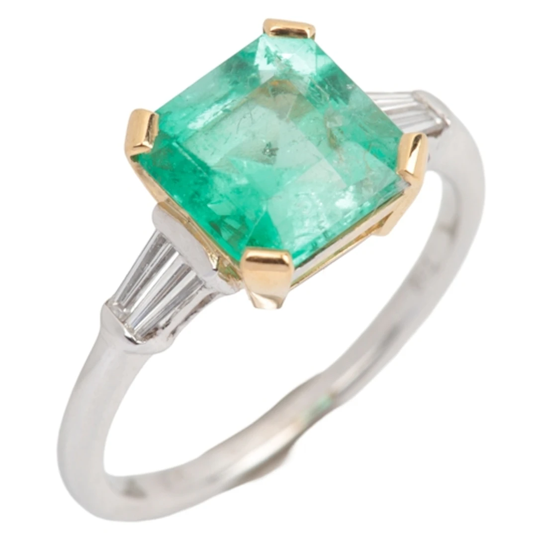 An emerald and diamond ring, claw-set with a step-cut emeral...