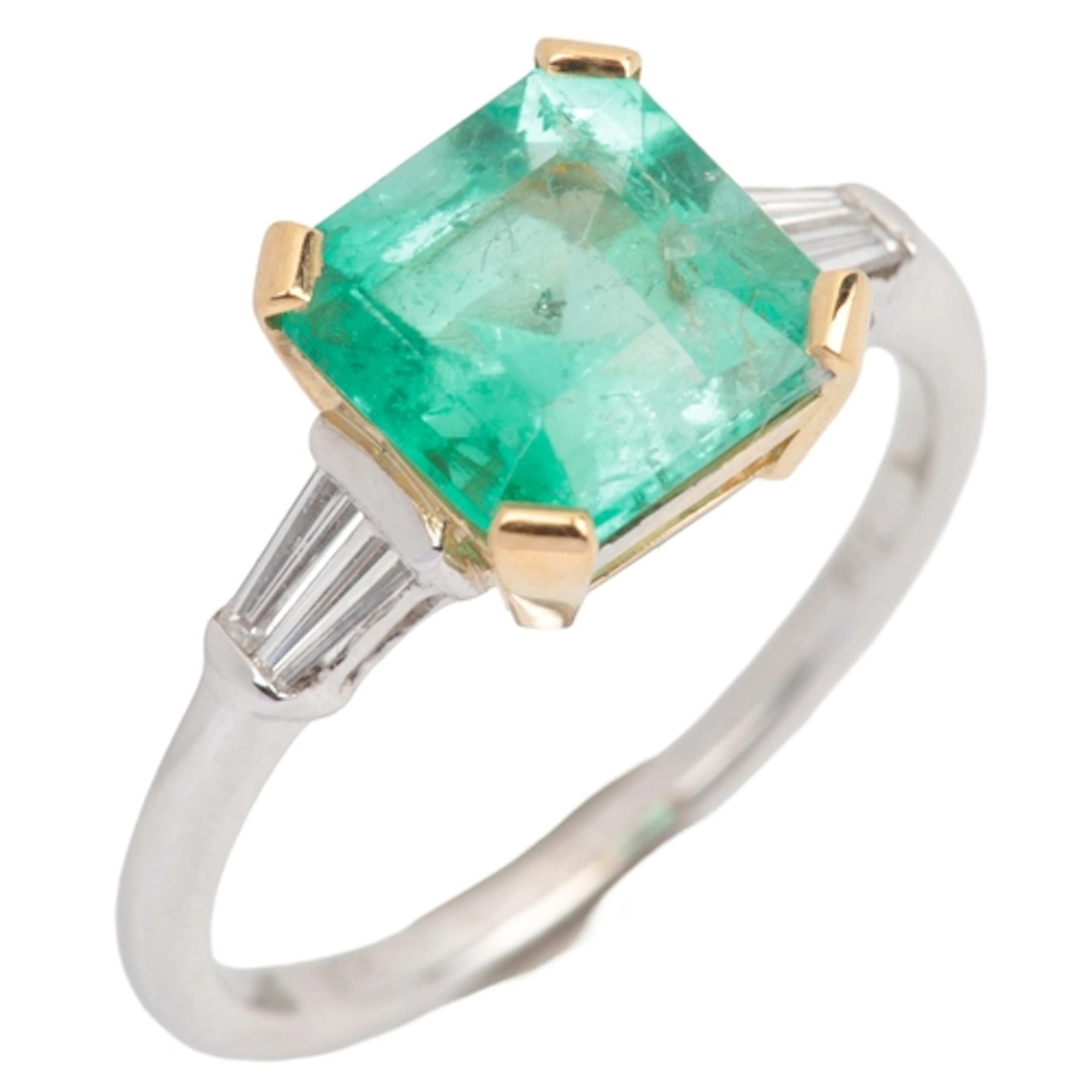 An emerald and diamond ring, claw-set with a step-cut emeral...