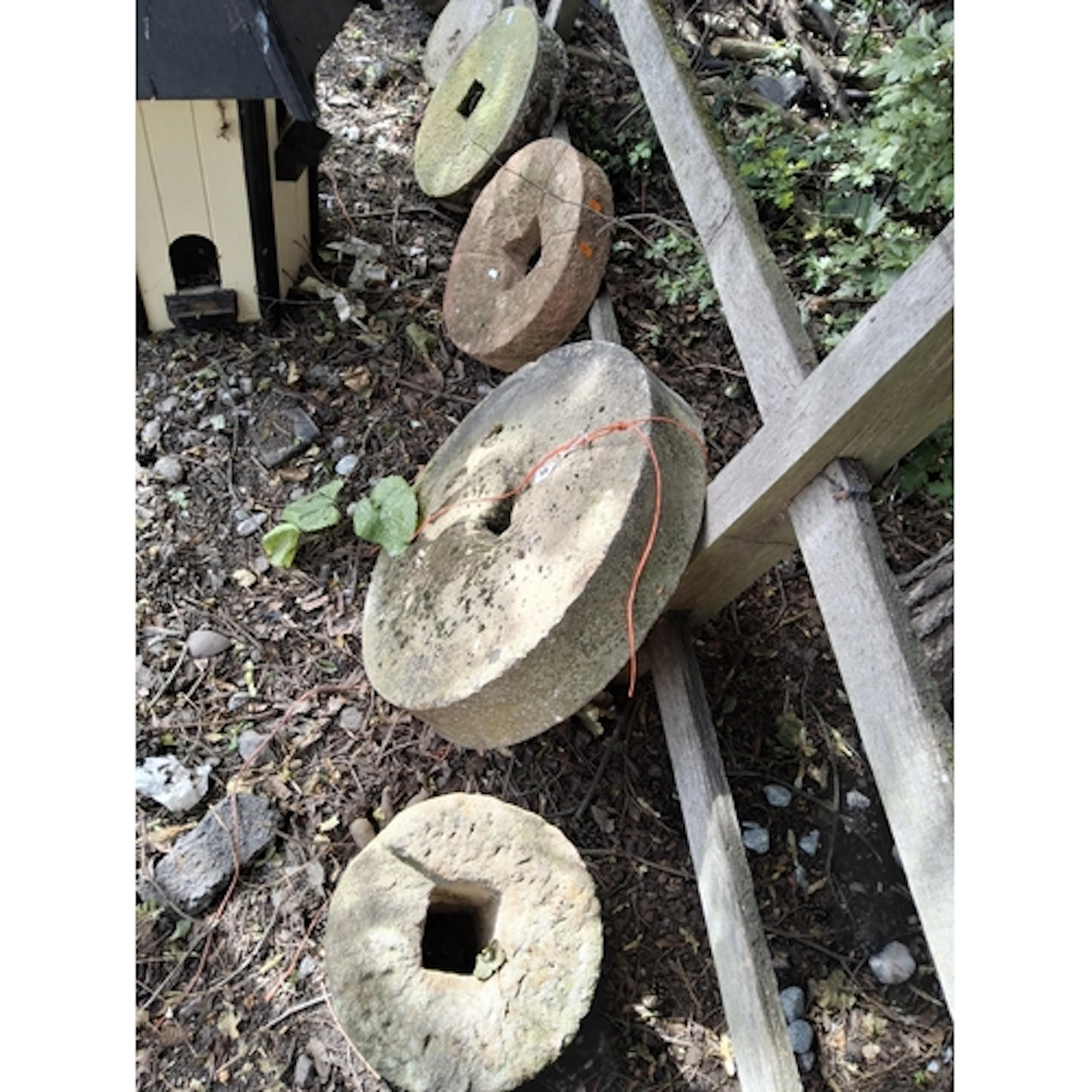 EIGHT VINTAGE QUERN STONES AND TWO WALL MASKS, the stones ar...