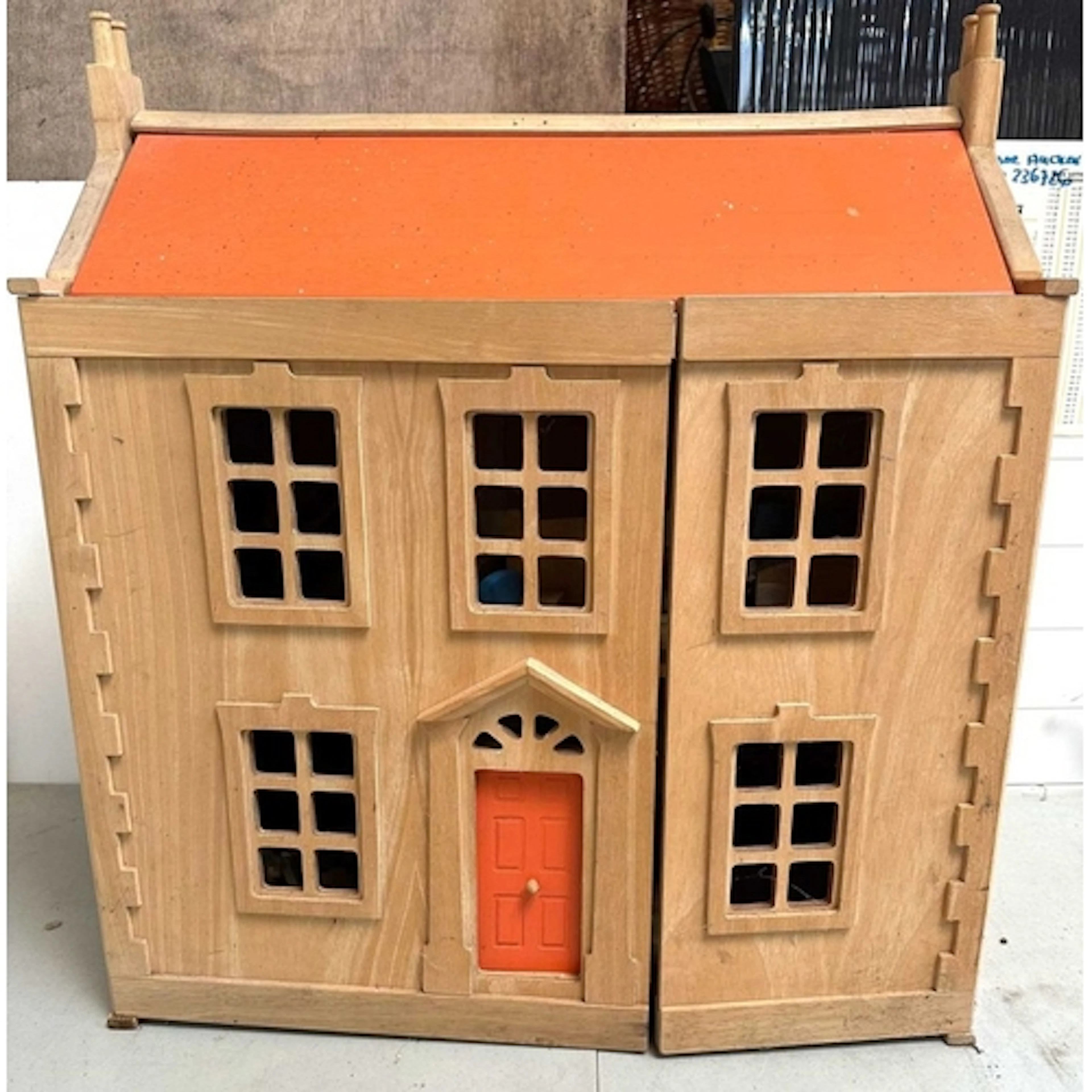 A Victorian doll house with a natural wood finish, orange ro...