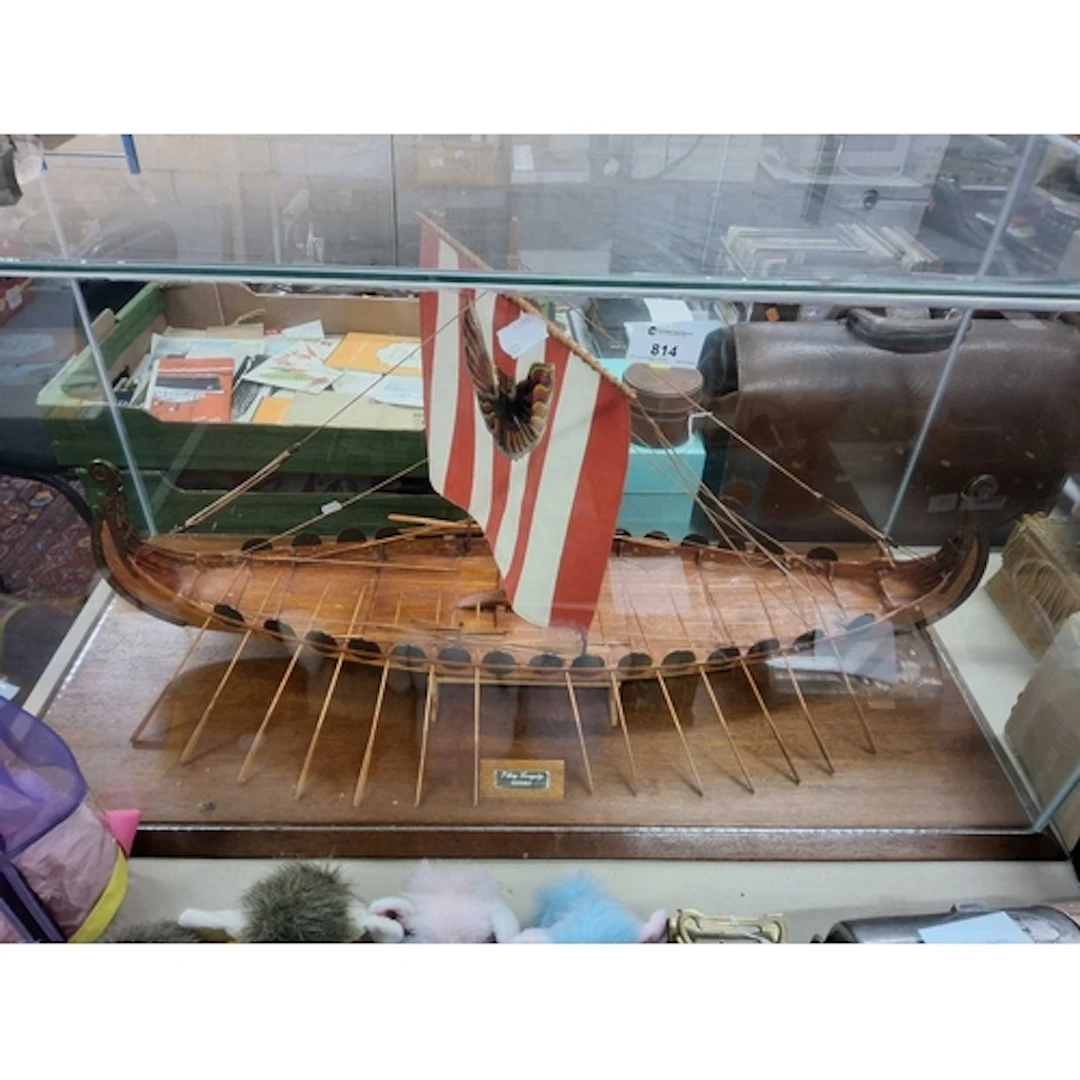 A WOODEN MODEL OF A VIKING LONGSHIP with a red and white sai...