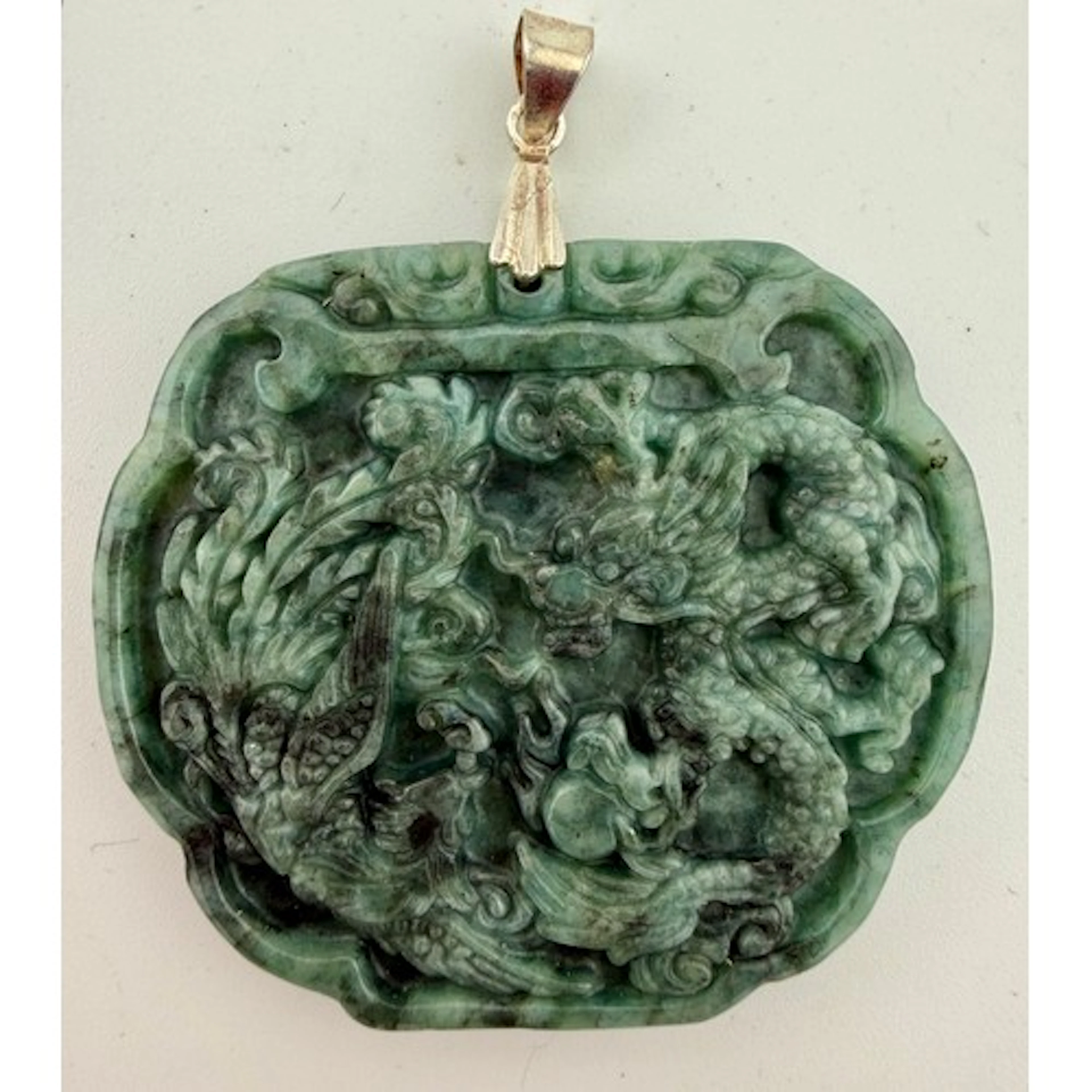 A Chinese carved and polished stone pendant with dragon and ...