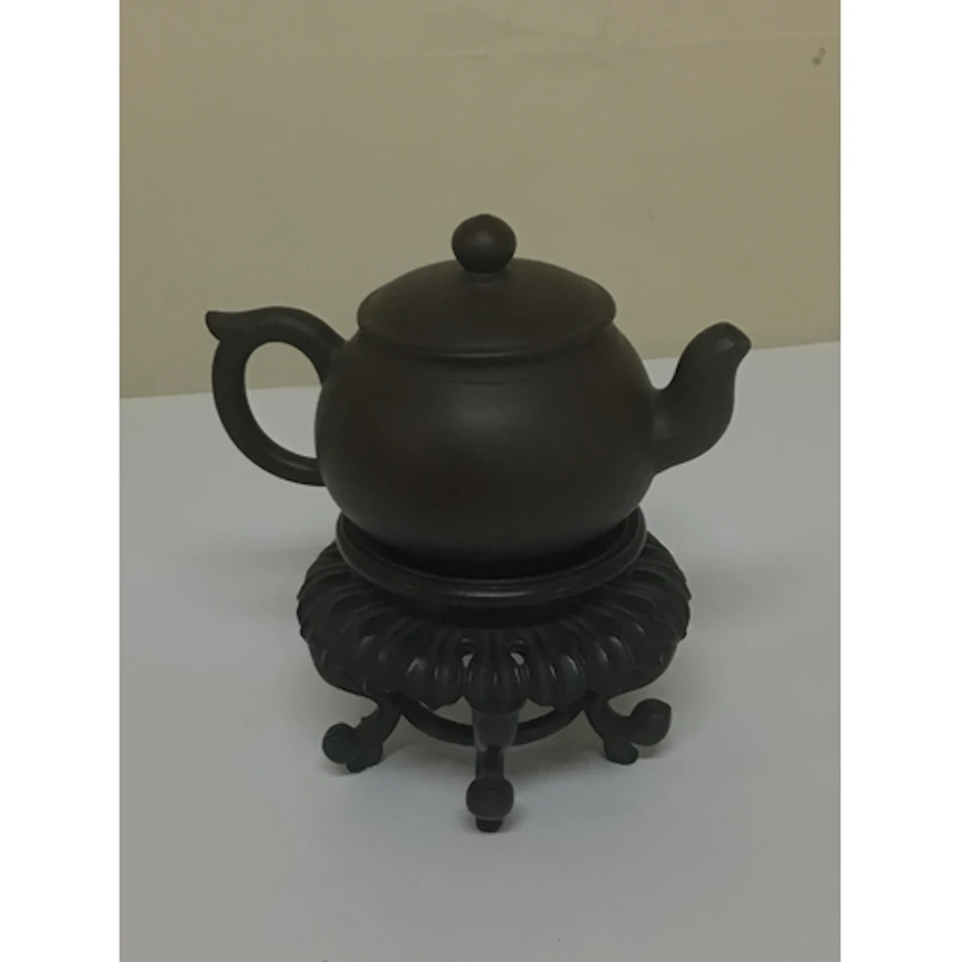 A minute Chinese earthenware tea pot on a hardwood stand the...