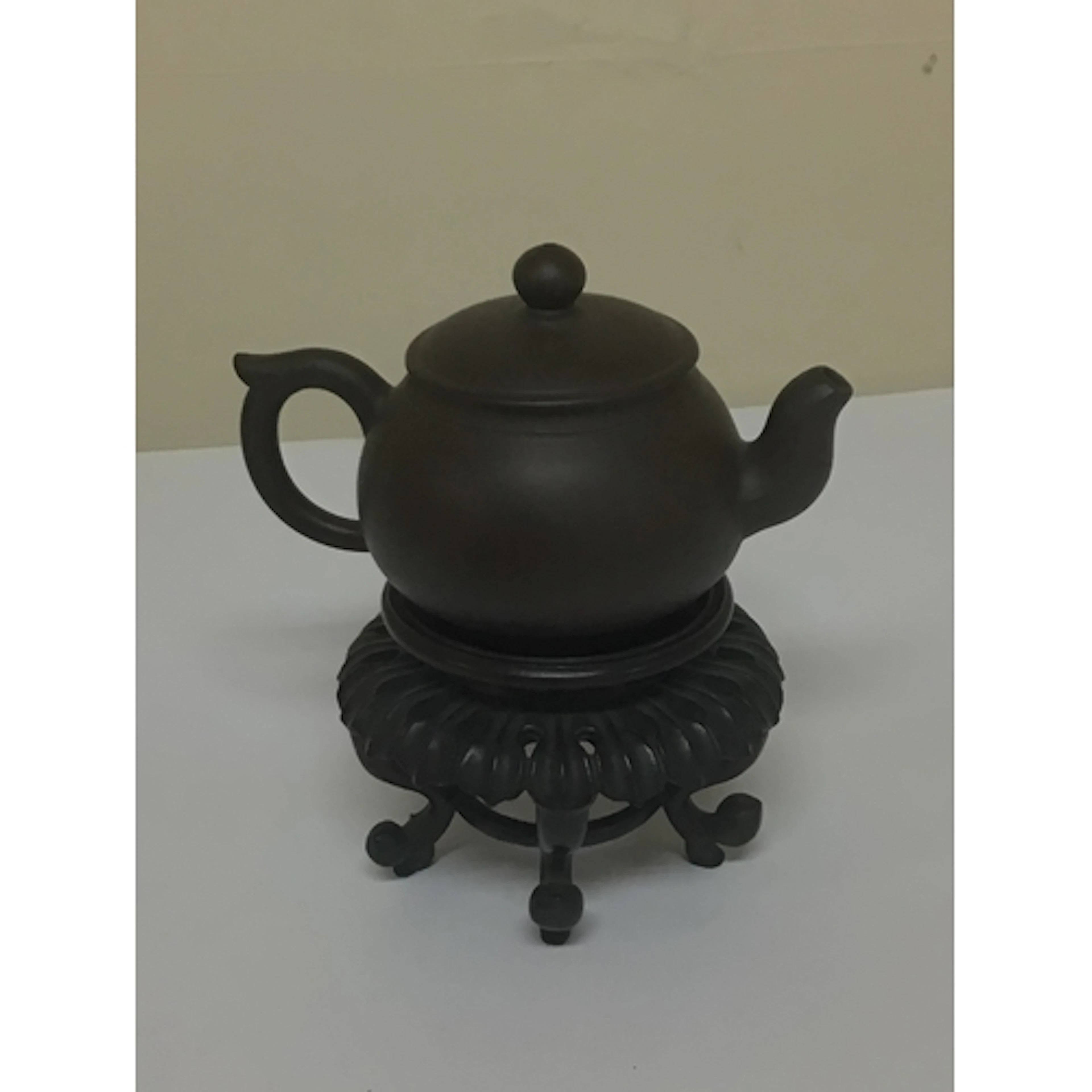 A minute Chinese earthenware tea pot on a hardwood stand the...