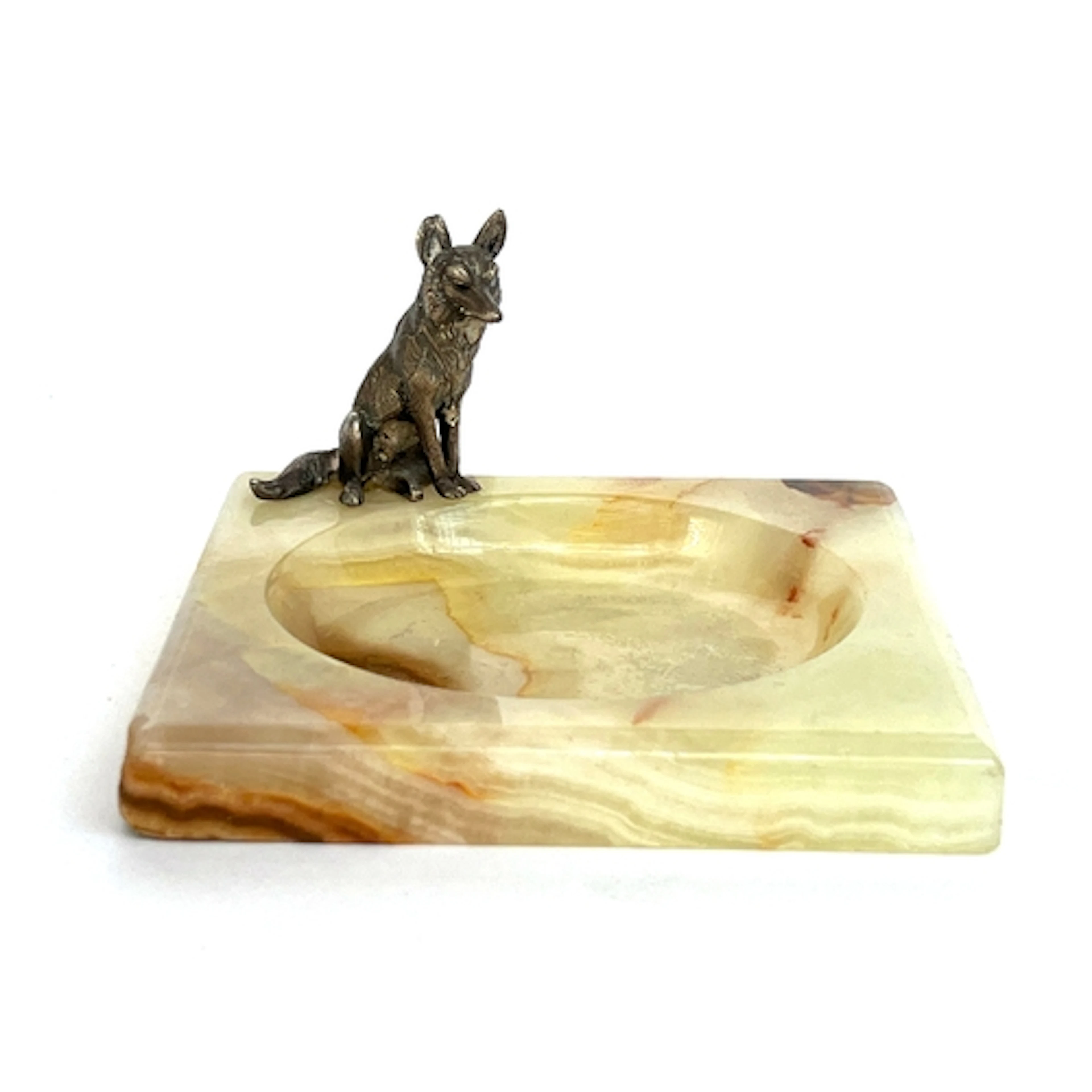 An onyx ashtray surmounted by a white metal seated fox, 10cm...