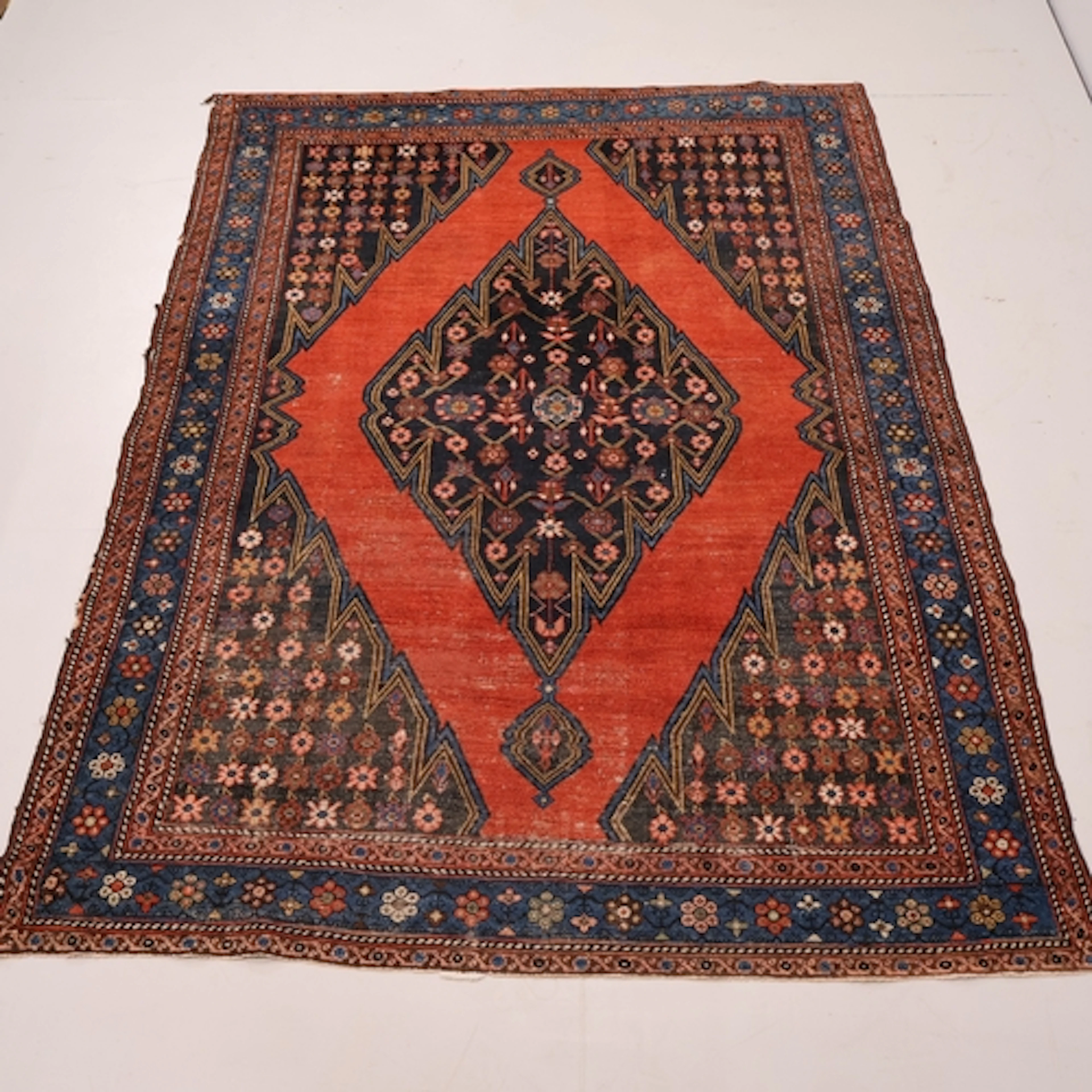 A red ground Persian rug with diamond lozenge and floral mot...